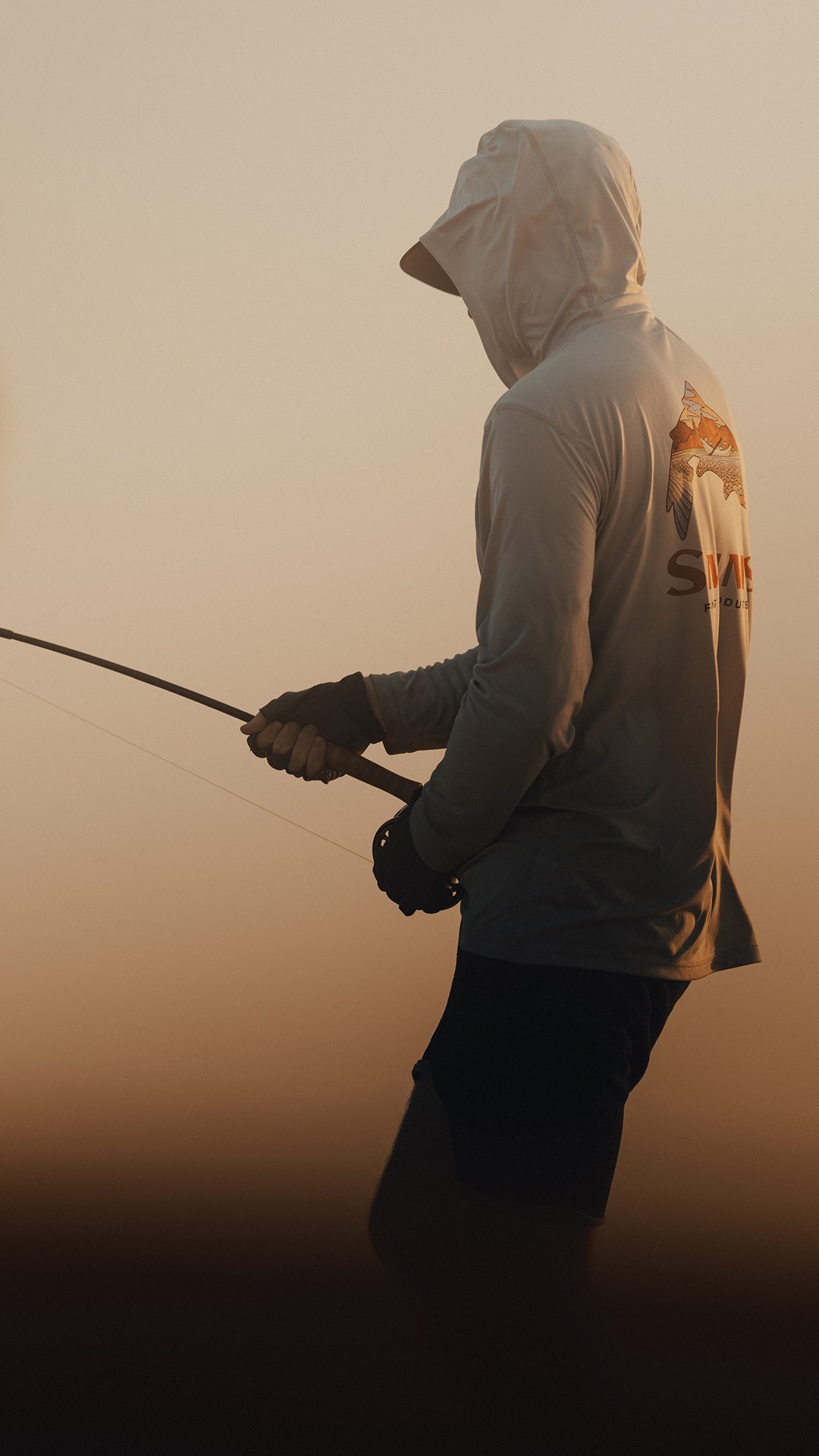 Angler holding a bent fly fishing rod during golder hour