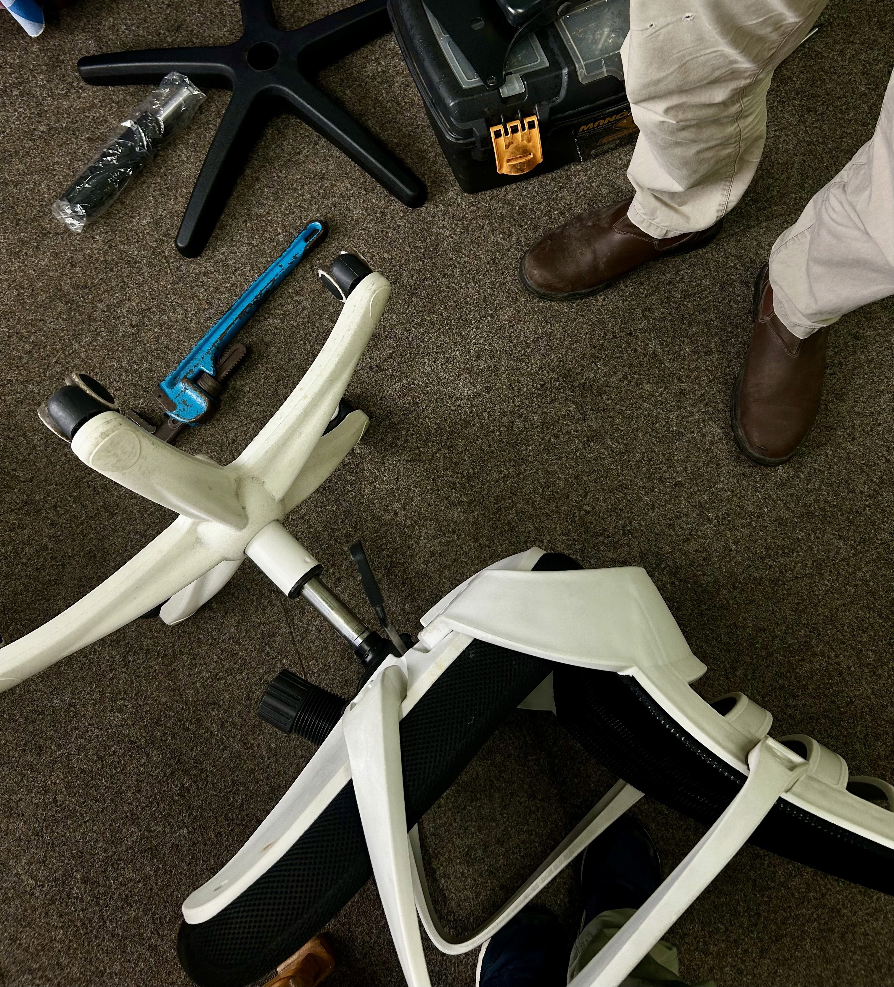 Office chair repair in progress with the chair on its side and tools /components packed out and ready to be used.