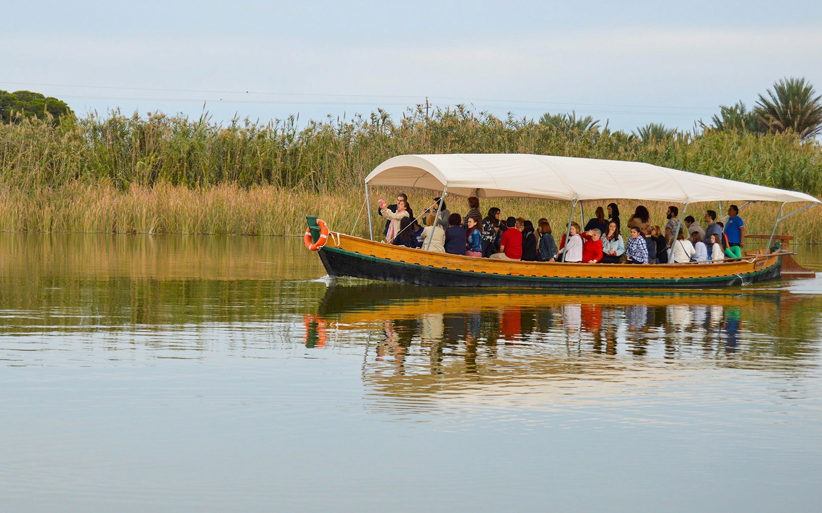 Boat ride with tourists in Albufera Natural Park, surrounded by reeds and calm water.