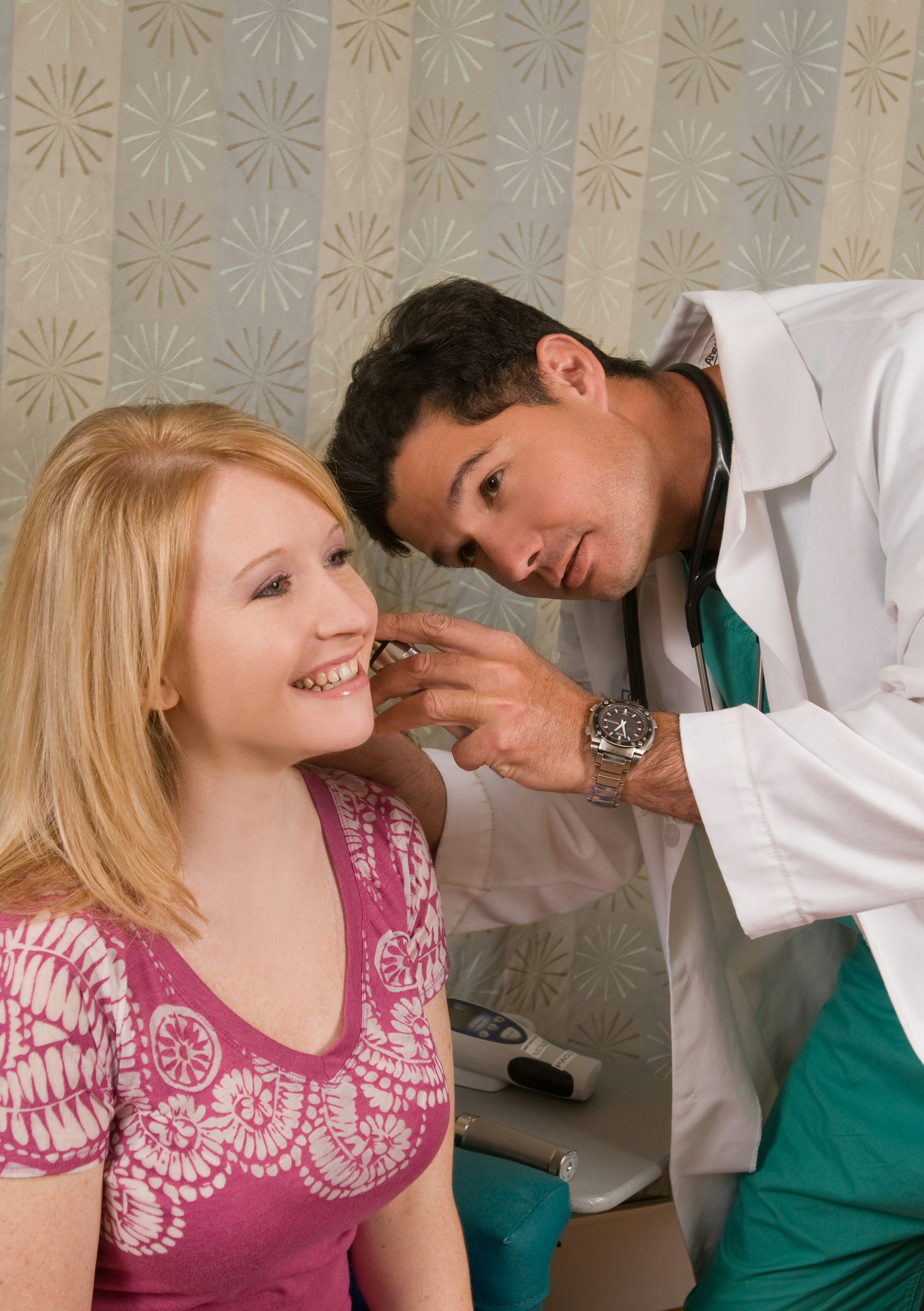 A doctor leans in closely to a smiling patient in a clinic setting, both looking relaxed and engaged in conversation.