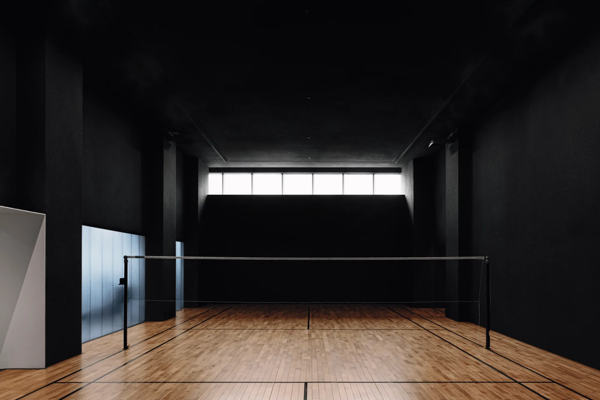 Timber floor of the PLAYA badminton court lit from high windows