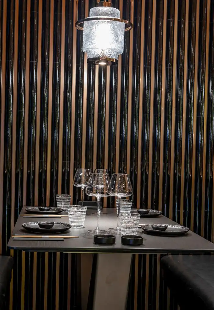 Table dressée sous une lanterne de cristal, devant un mur noir cannelé