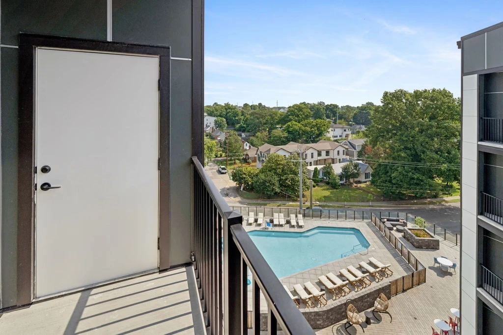 A balcony featuring a pool overlooks a vibrant city skyline under a clear blue sky.
