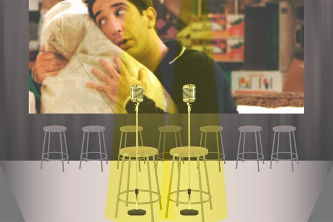 A projection of a man holding a baby is visible on a screen behind a row of six gray stools. Four microphones are positioned in front of the stools, casting a yellow glow. The floor is light gray, and the wall behind the screen is dark gray.