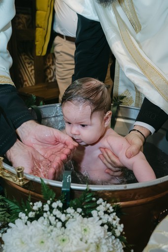 Momentul scufundării în cristelniță la botez ortodox.