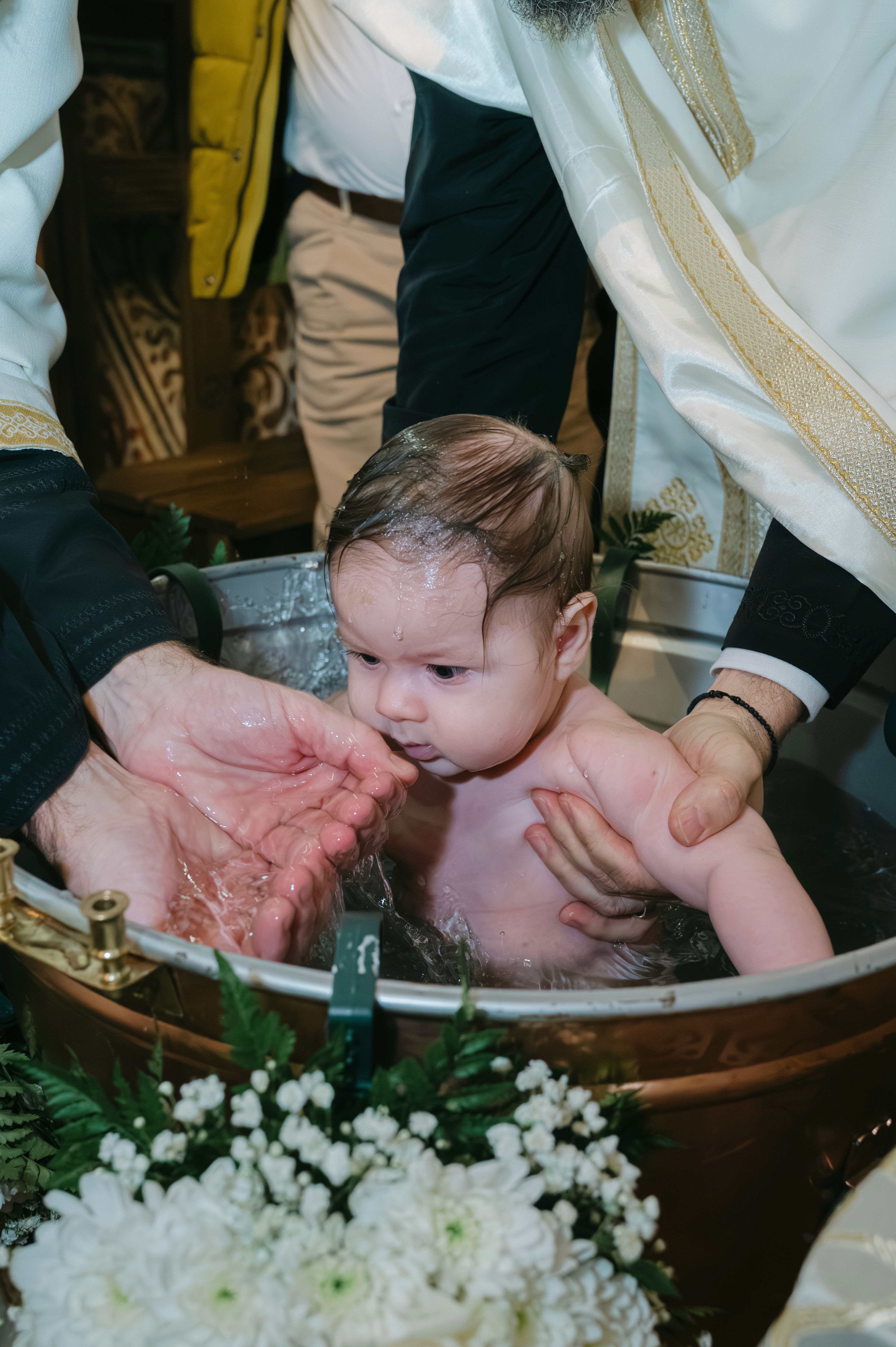 Momentul scufundării în cristelniță la botez ortodox, fotografie realizată în București.