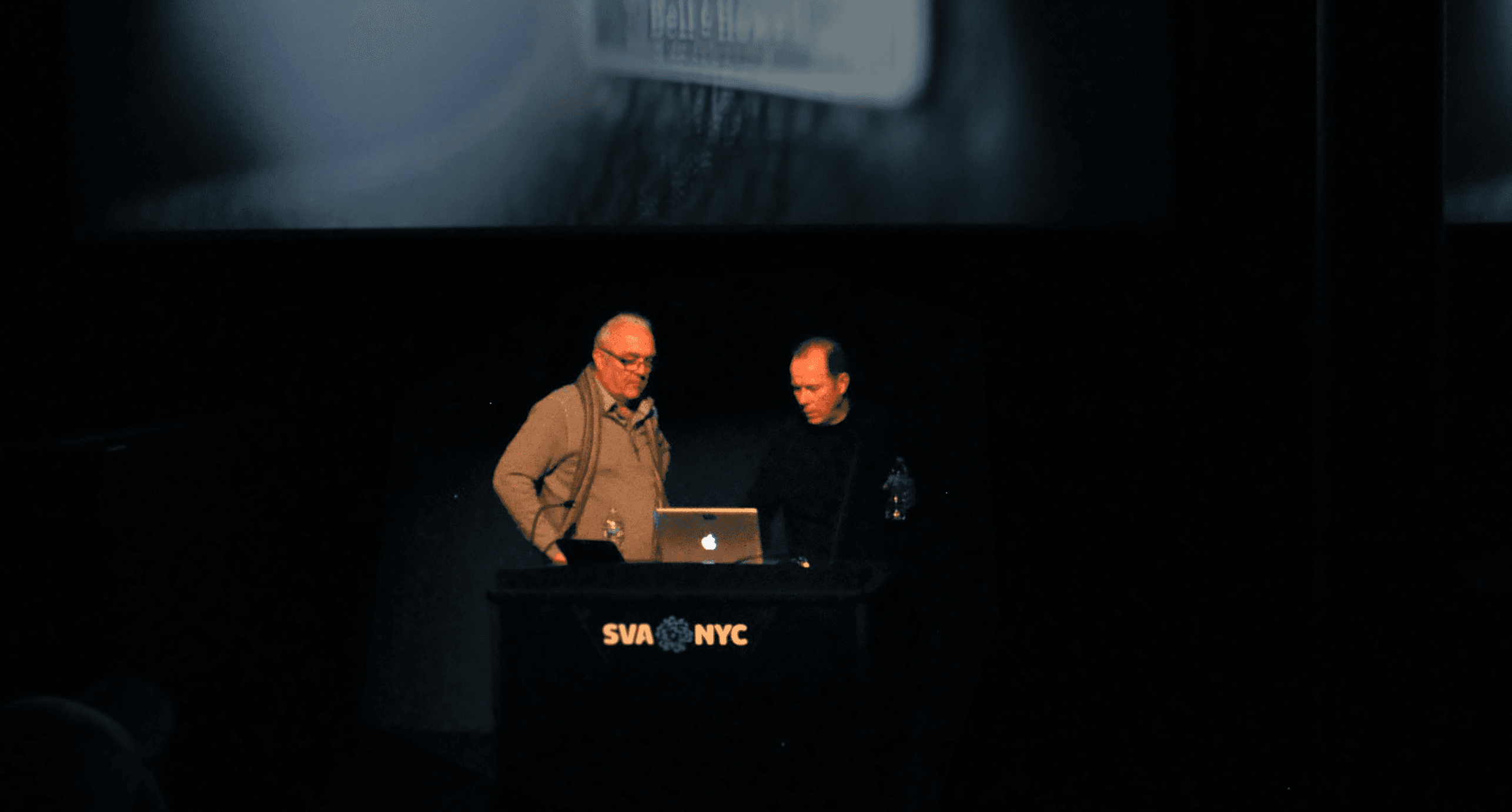A photo of two people giving a lecture from a laptop on a SVA NYC stand.