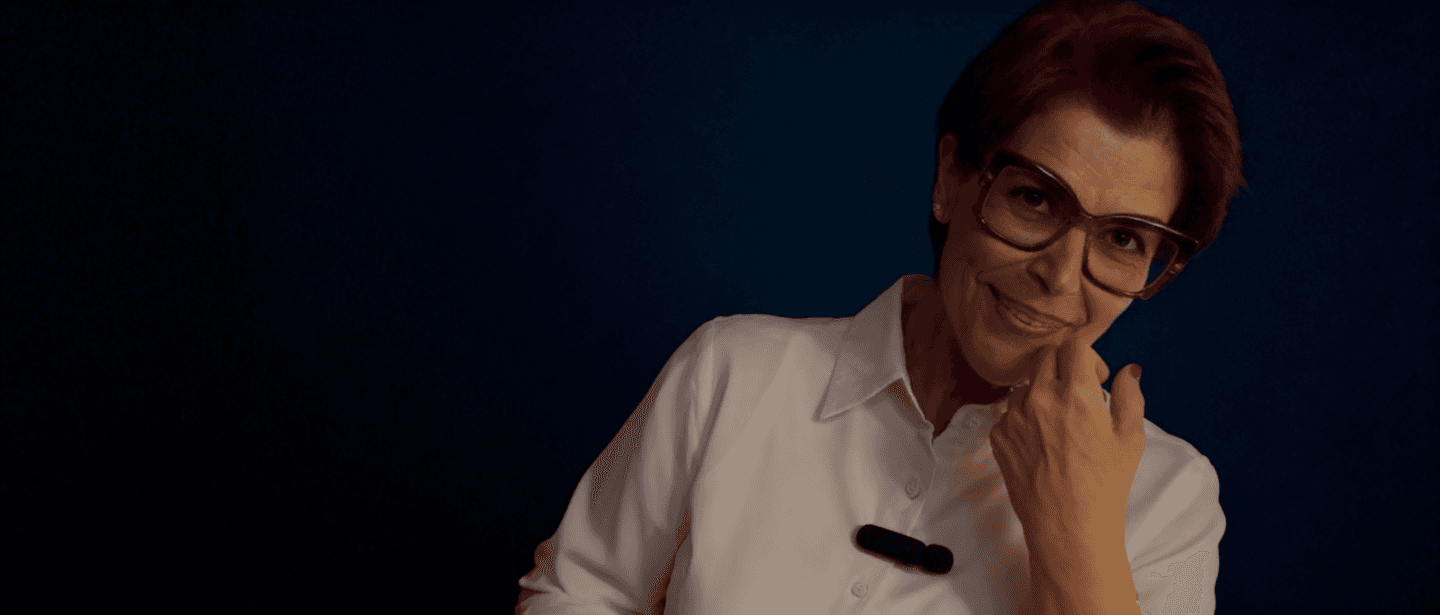 woman sitting on brown wooden chair while using silver laptop computer in room