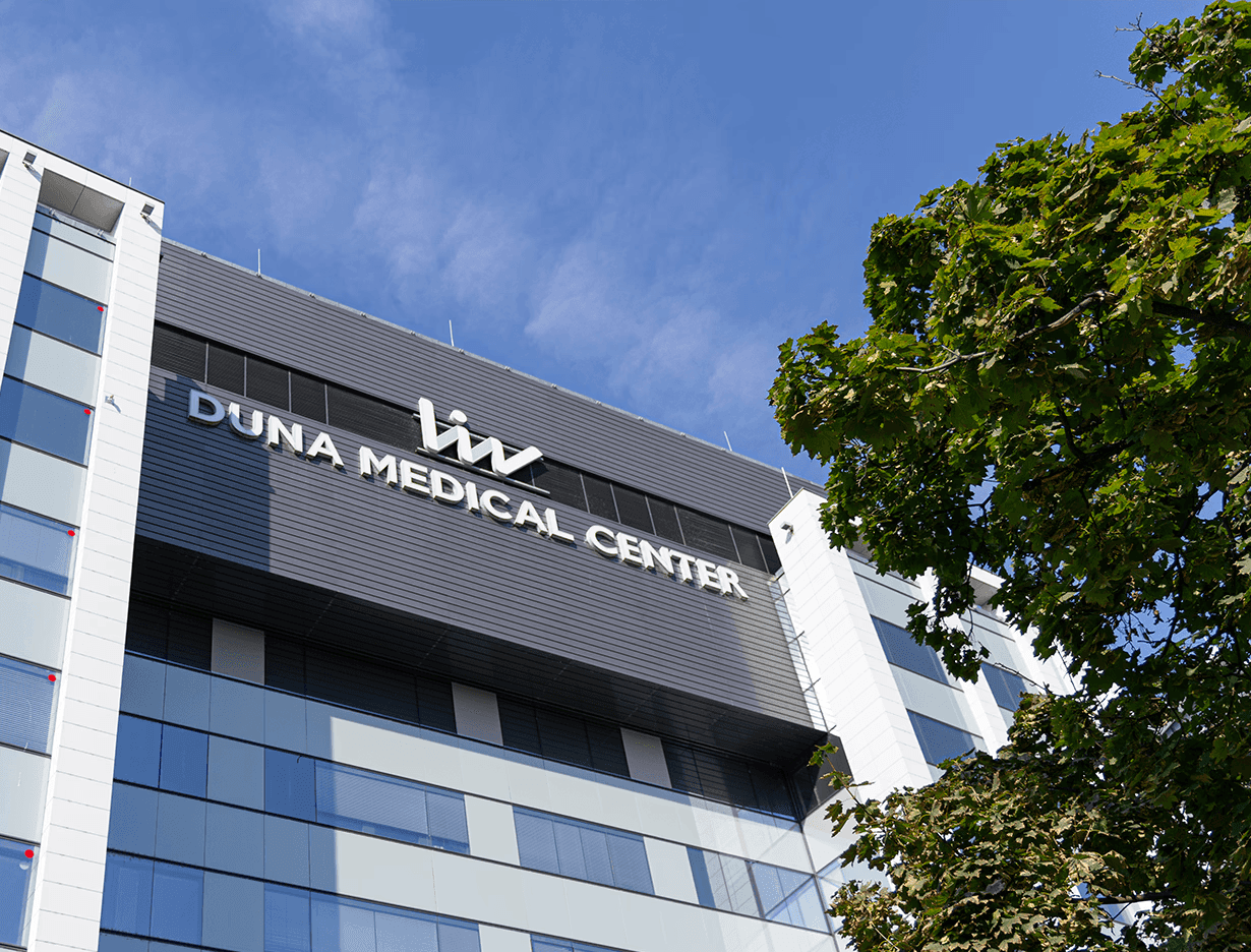 image of Imperial Dental's modern treatment room featuring blue dental equipment, a monitor with the clinic’s logo, and natural light from large windows overlooking a park.