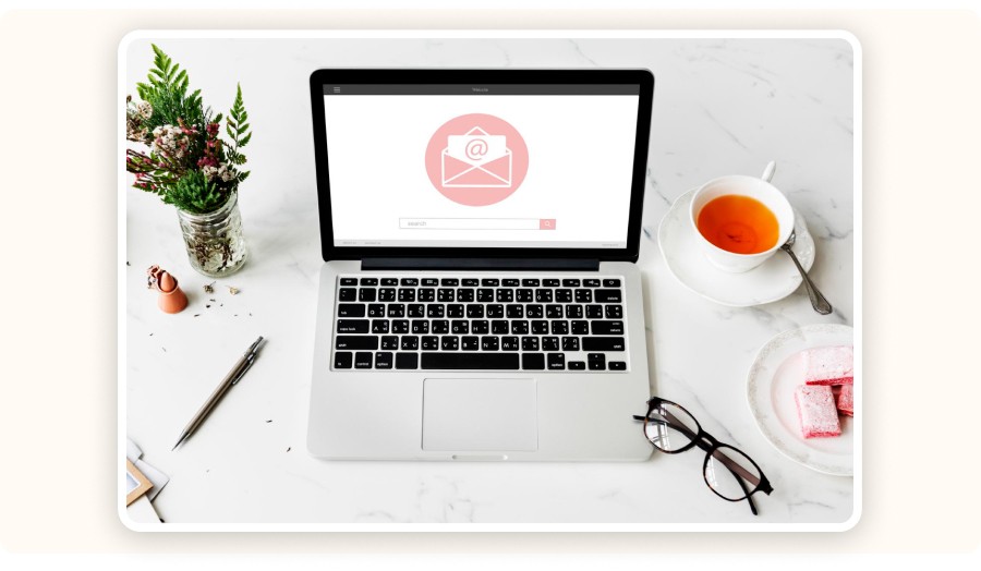 Laptop displaying email interface on desk with tea and stationery