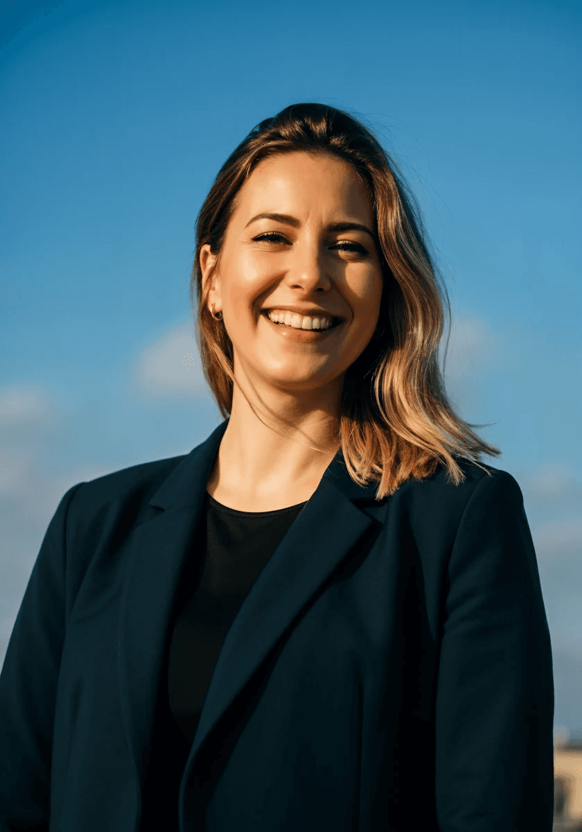 Smiling woman in a dark blazer against a blue sky