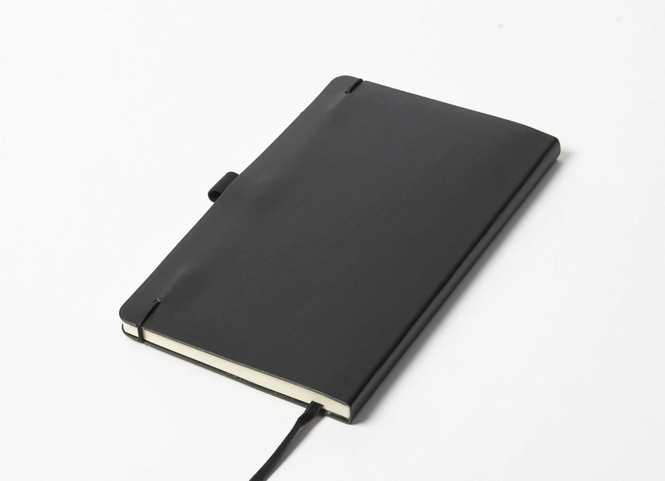 Back angled view of black notebook showing elastic strap connection and pen loop.