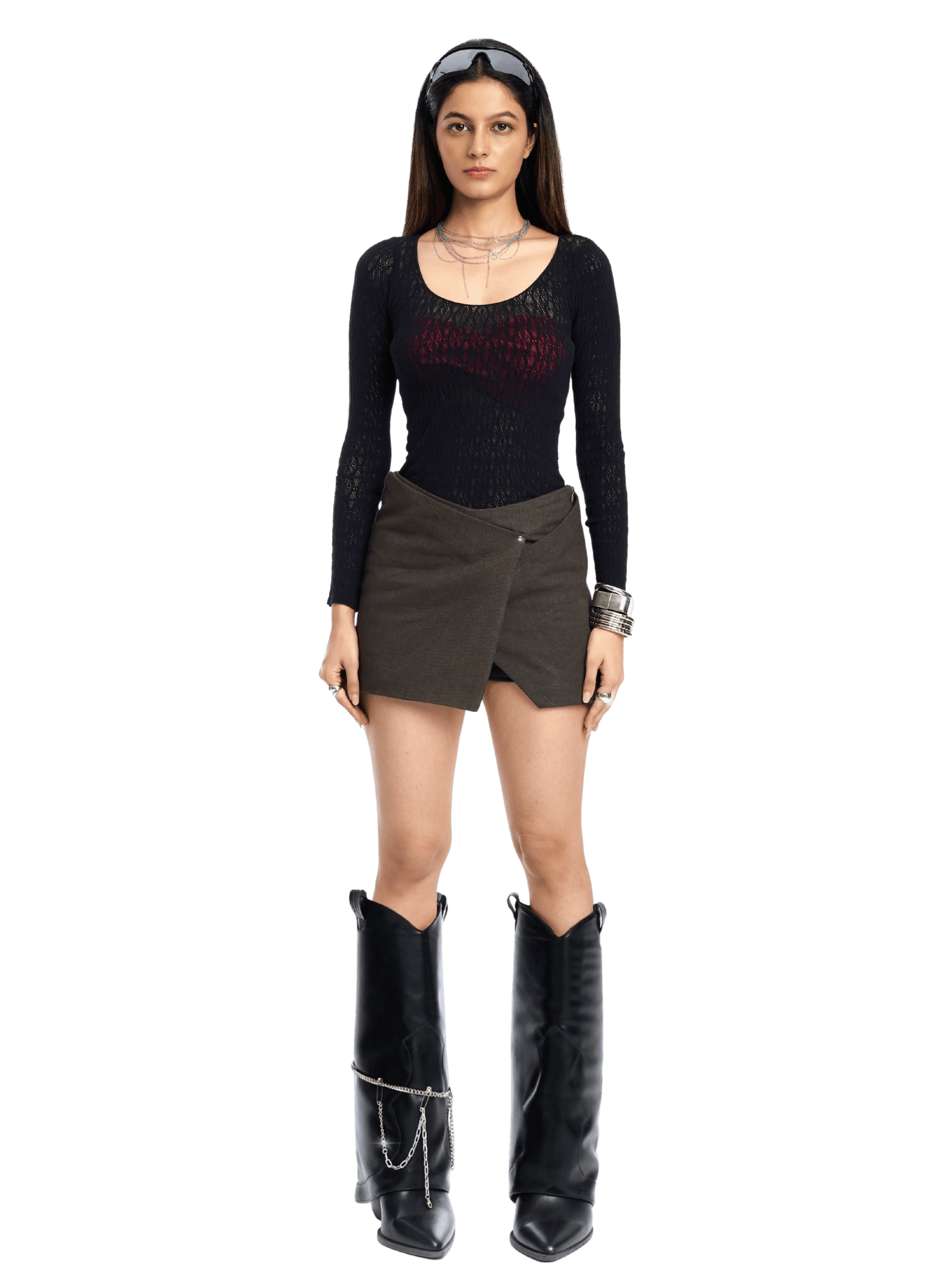 Woman wearing a black long-sleeve top, brown skirt, and black boots on a white background