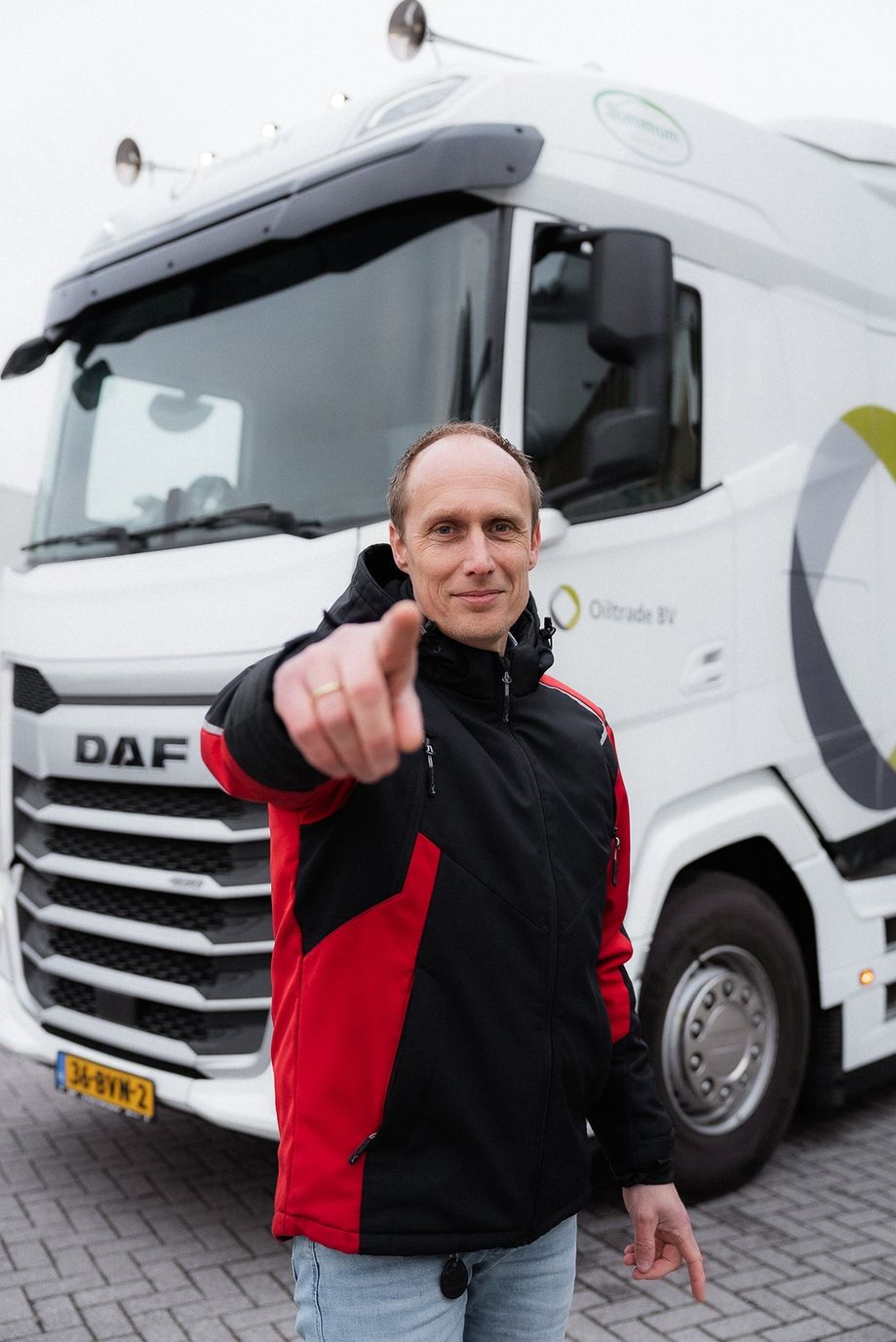 Vrachtwagenchauffeur bij Oiltrade aan het werk wijzend naar de camera