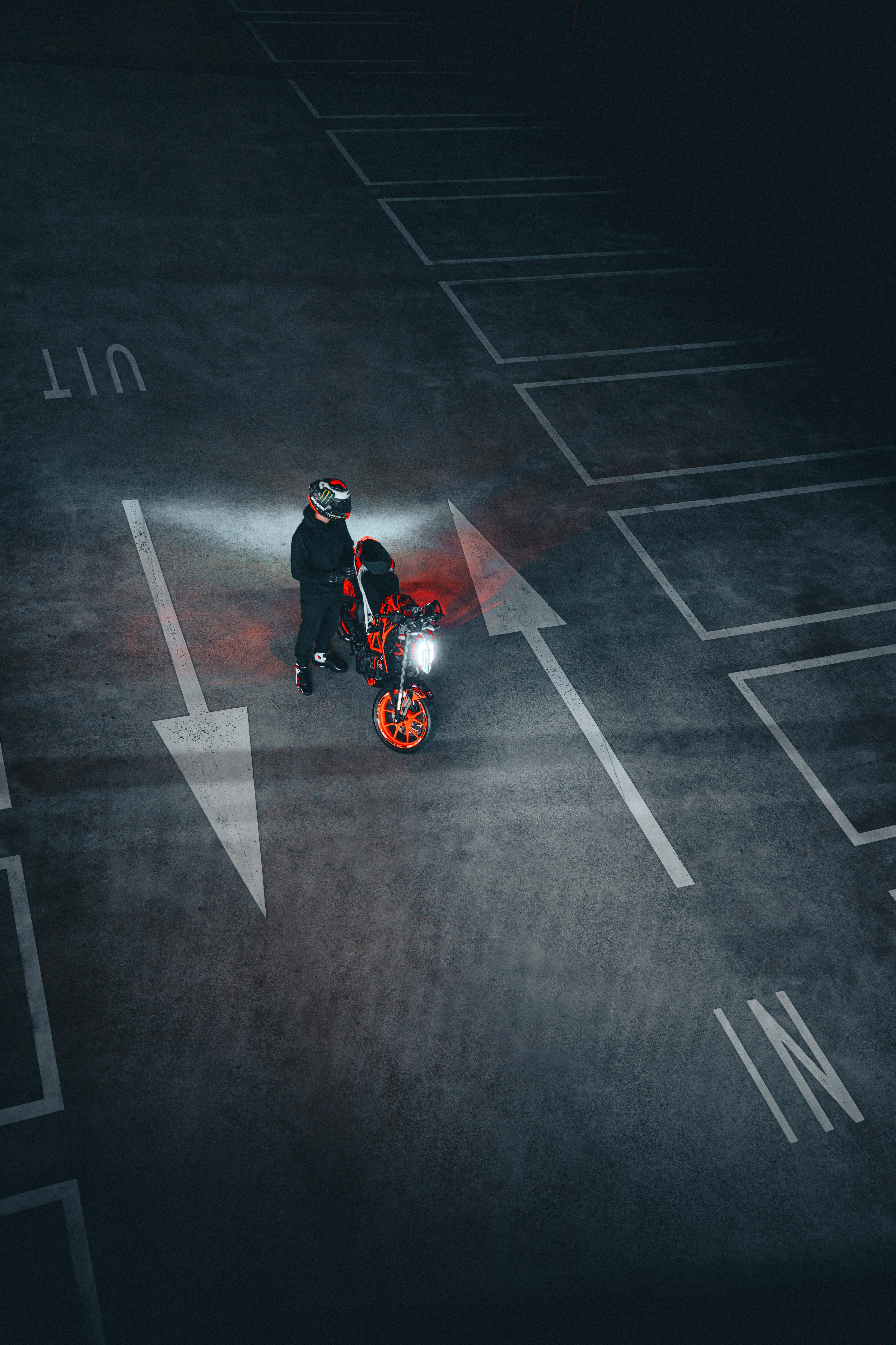 A person with a motorcycle in a parking lot.