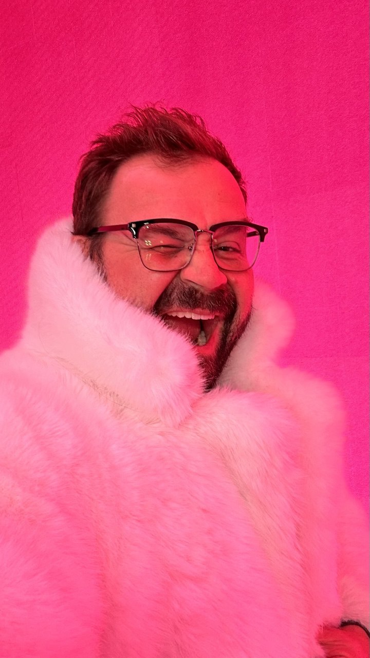 Person, holding a white rose behind his back with one arm on a light blue background