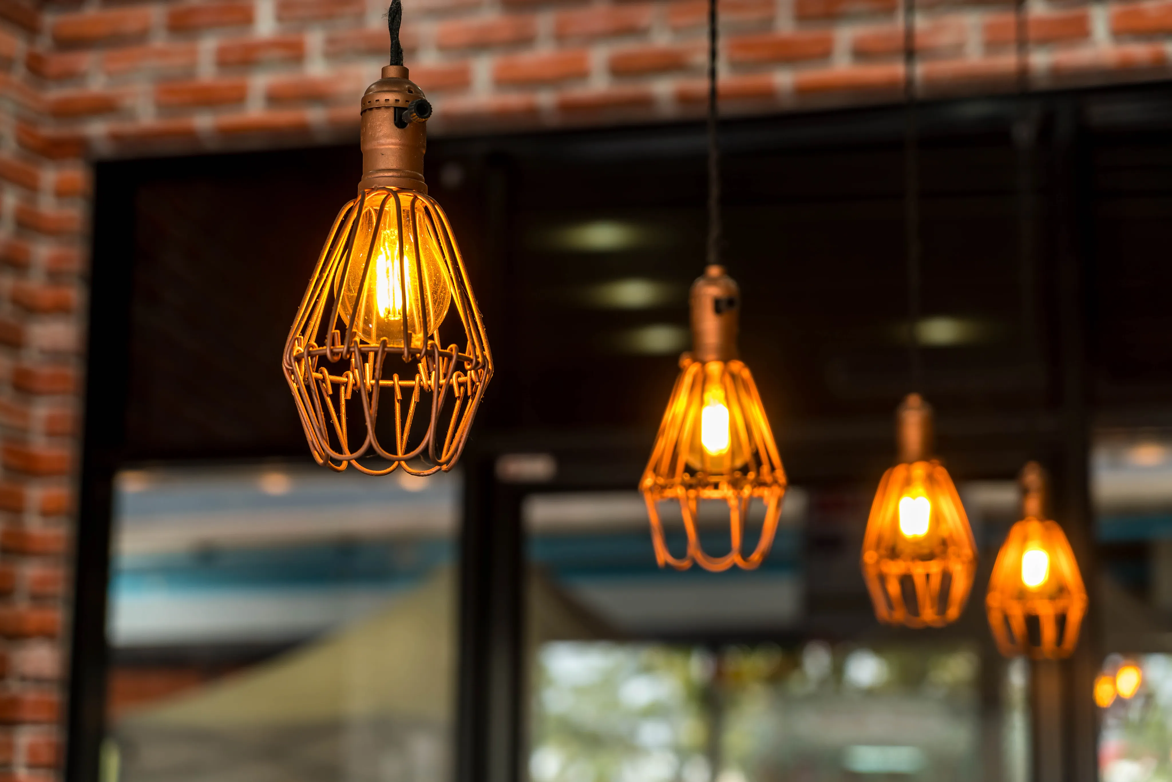 Industrial office workspace with glowing exposed Edison bulb pendant lights over wooden desks.