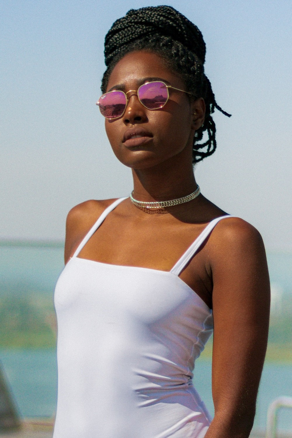 Editorial fashion photography of a woman model wearing a white swimsuit with pink glasses for Be My Guest brand