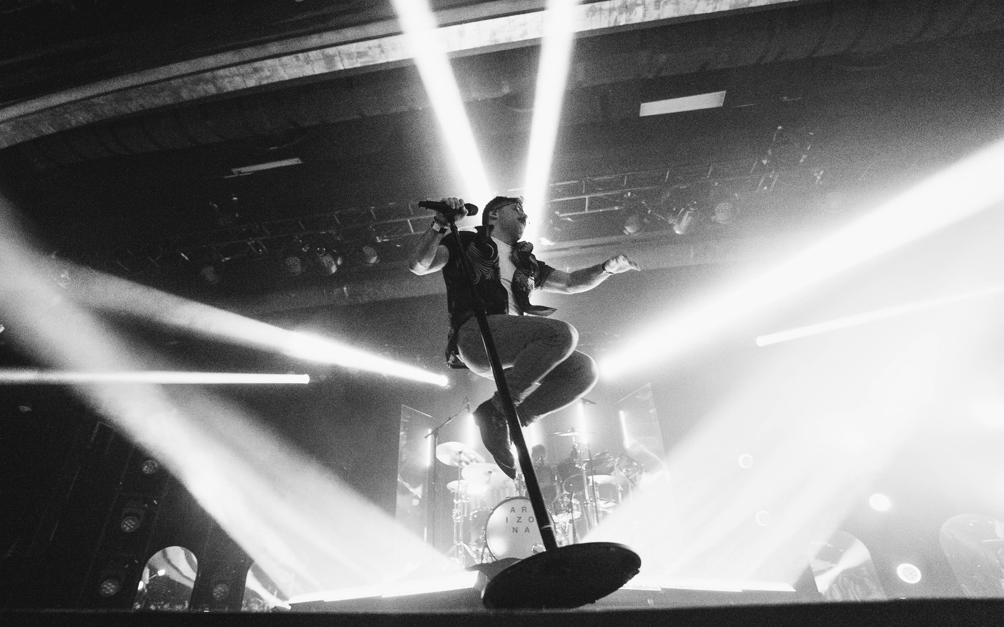 The lead singer of the band A R I Z O N A jumping through beams of light at their concert in Phoenix, Arizona in front three mirror monoliths