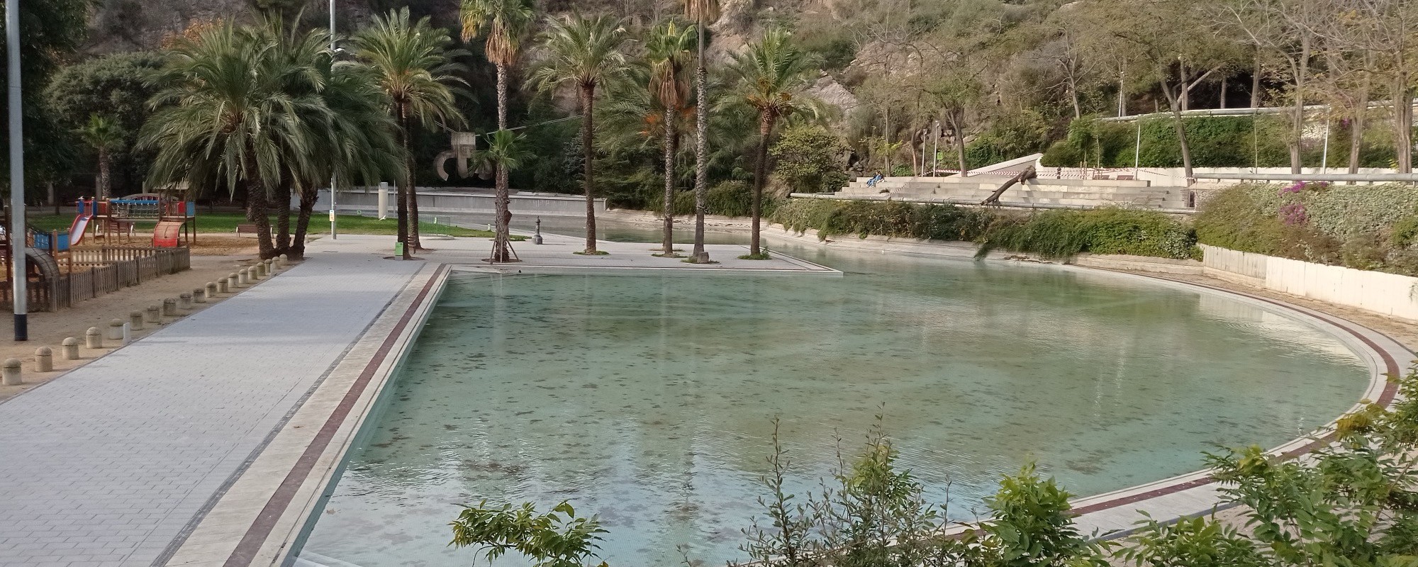 Lake at Parc de la Creueta del Coll with palm trees and a playground
