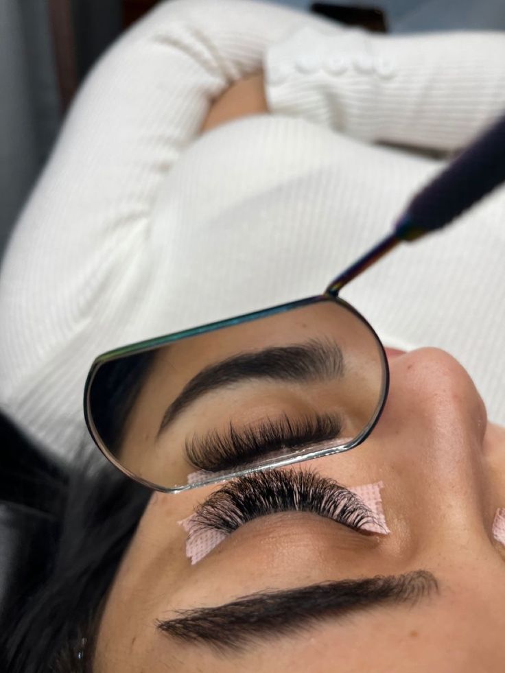 Pose d’extensions de cils volume russe en cours – reflet dans un miroir professionnel montrant la symétrie et la densité des cils, prestation de beauté du regard réalisée par une technicienne experte.