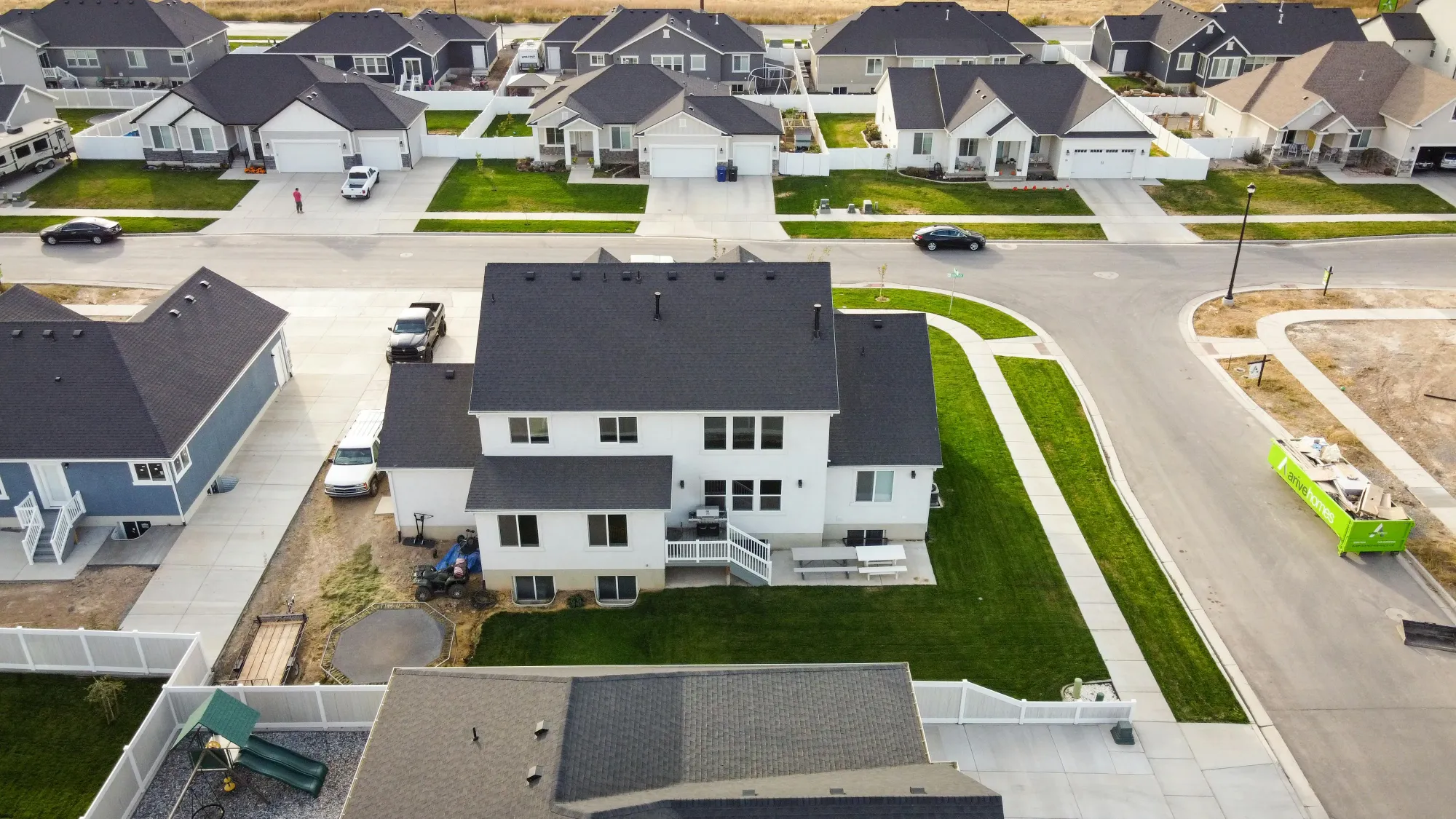 Aerial view of a two story suburban home with a fenced backyard, patio, and surrounding neighborhood streets and houses. This real estate drone videography perspective shows the home’s lot size and layout within the community, helping a drone videographer highlight both the property and its neighborhood setting.