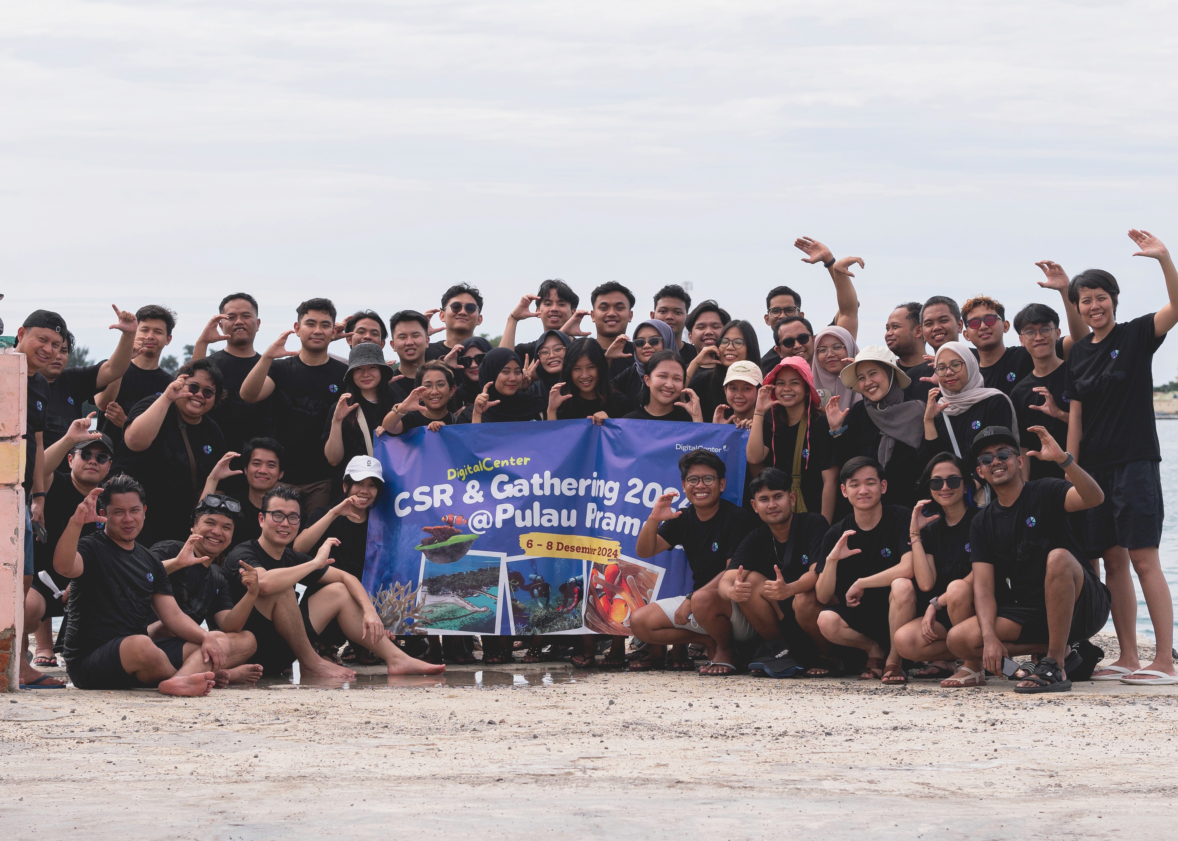 A large group photo of diverse team members gathered in an industrial-style space with arched ceiling.