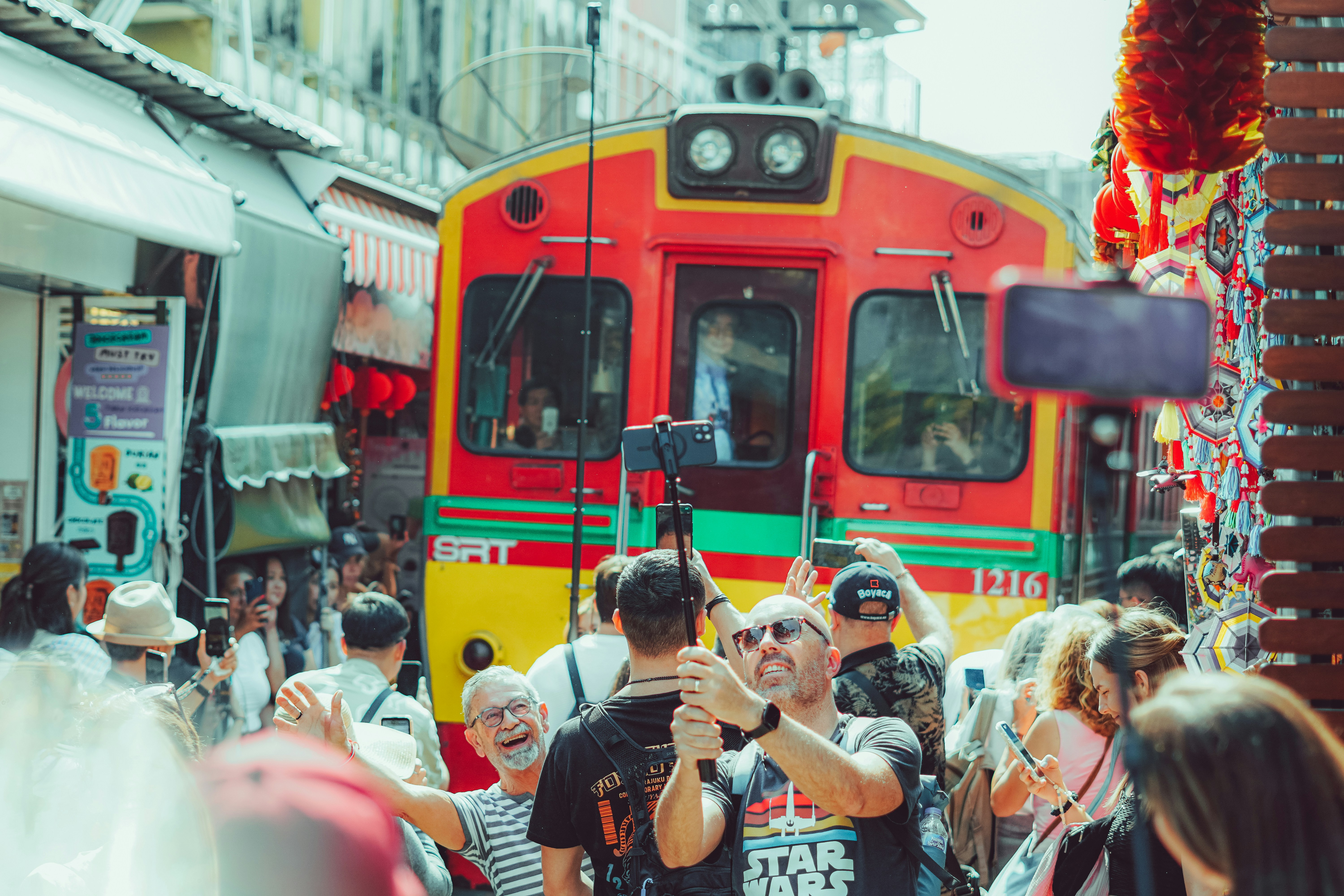 People take selfies near a colorful train.