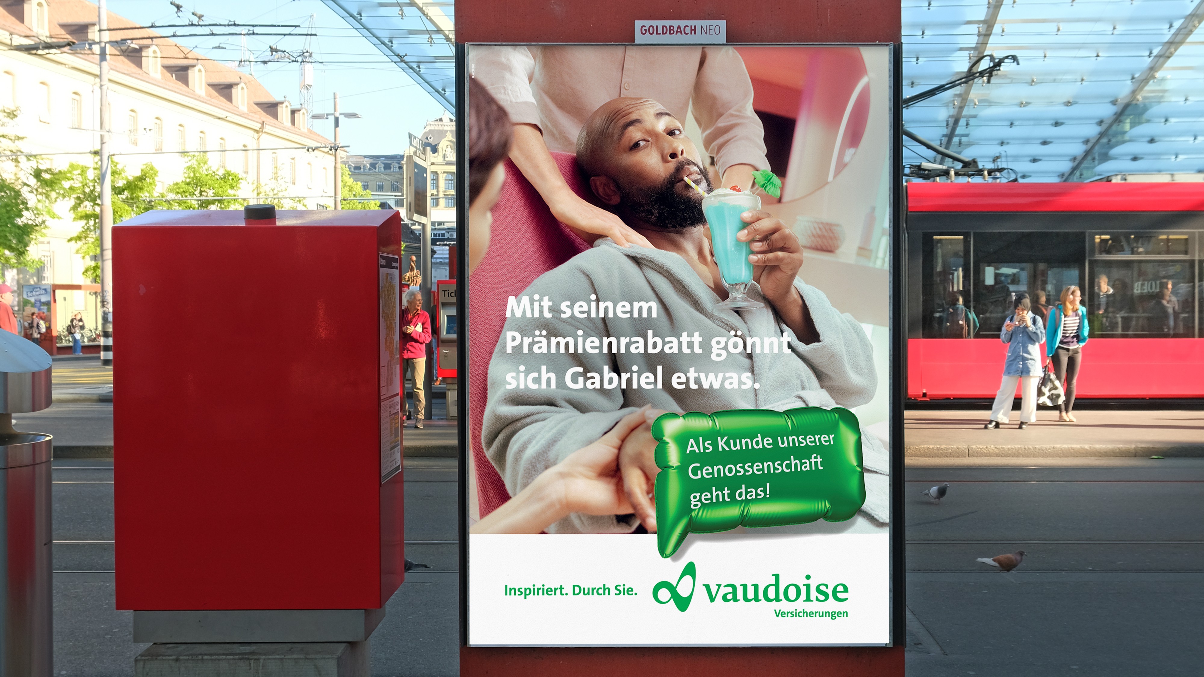 Billboard of a man in a spa treatment seat, with German text about Vaudoise Versicherungen insurance discounts.