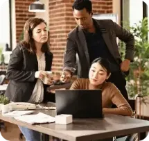People looking at a laptop while another person looks on.