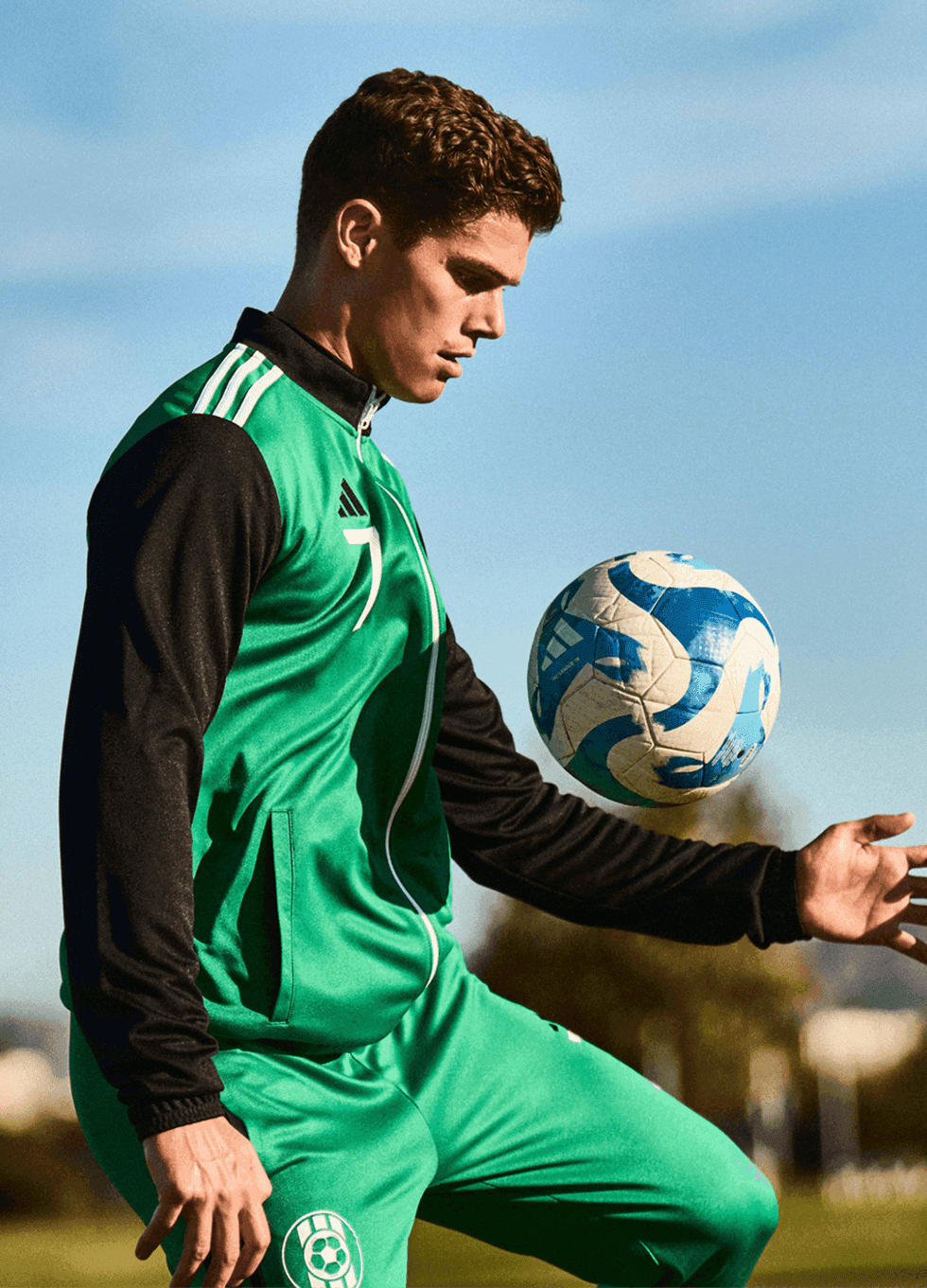 Football player in a green custom jersey holding a ball, representing personalised teamwear.