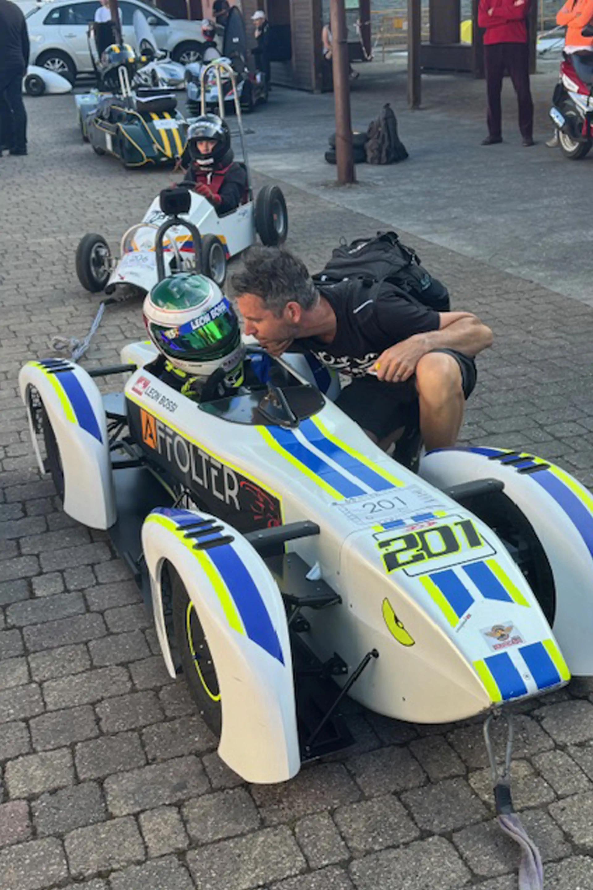 Caisse à savon blanche et bleue numéro 201 avec pilote au paddock