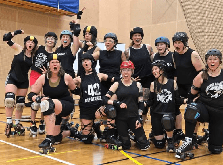 A roller derby team posing in a line for a photo.