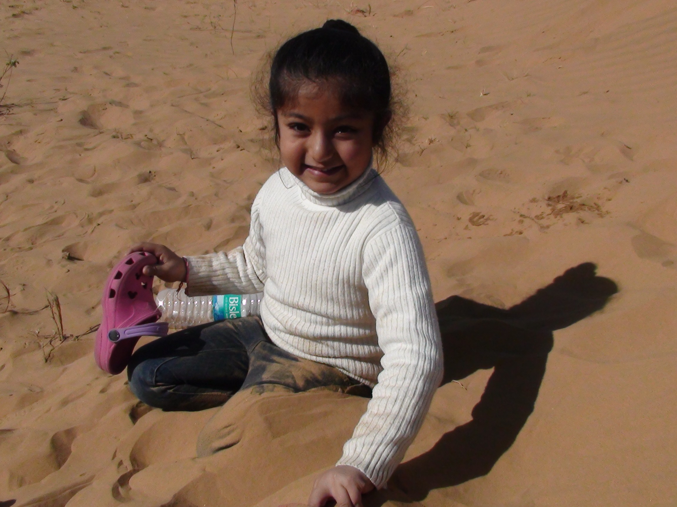A close-up of a pink cocktail in a martini glass, set against a nighttime background with soft, blurred colors.