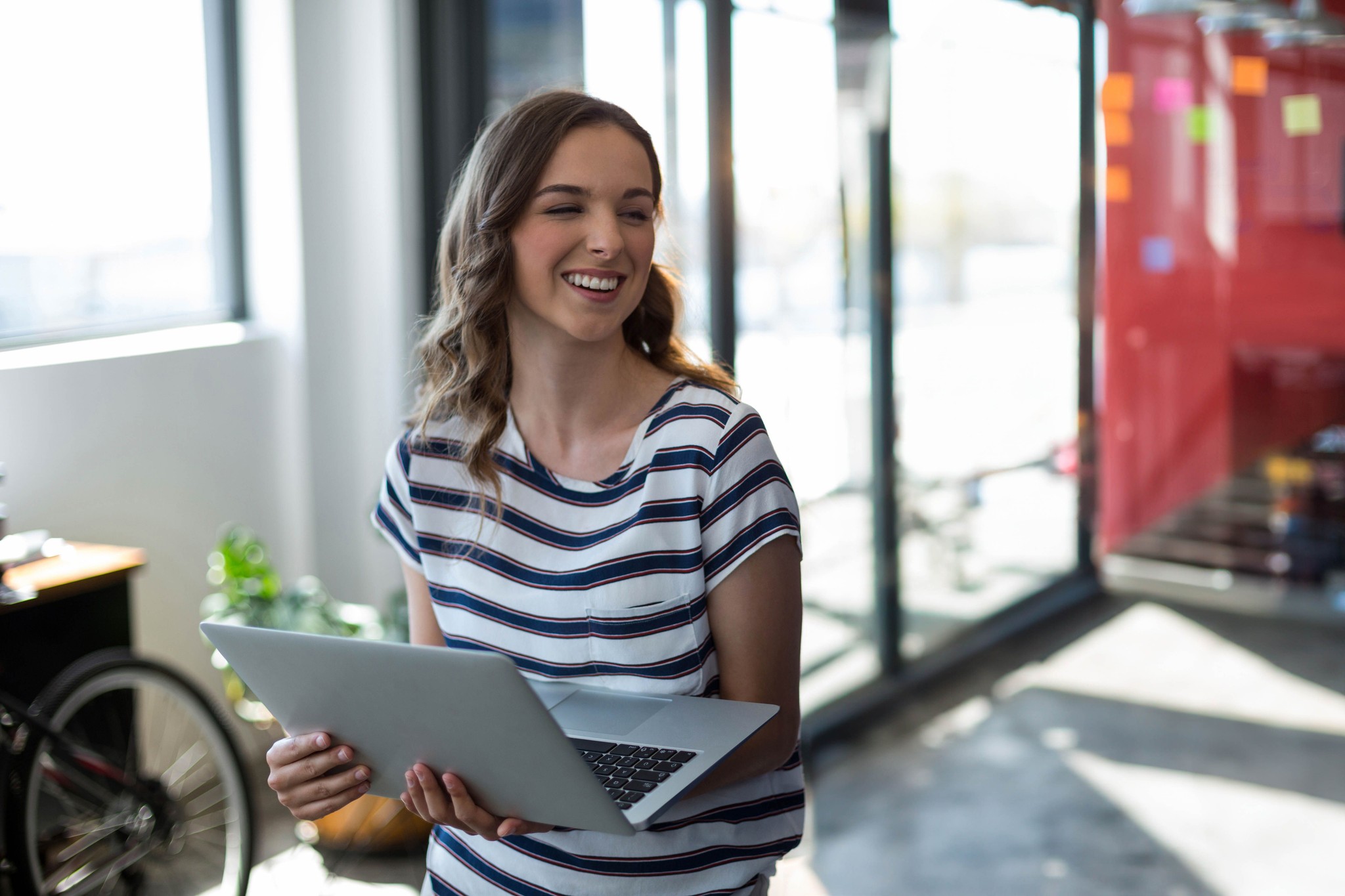 Smiling young woman using laptop in modern office