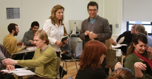 A group of people sitting in a classroom in smaller groups and discussing.