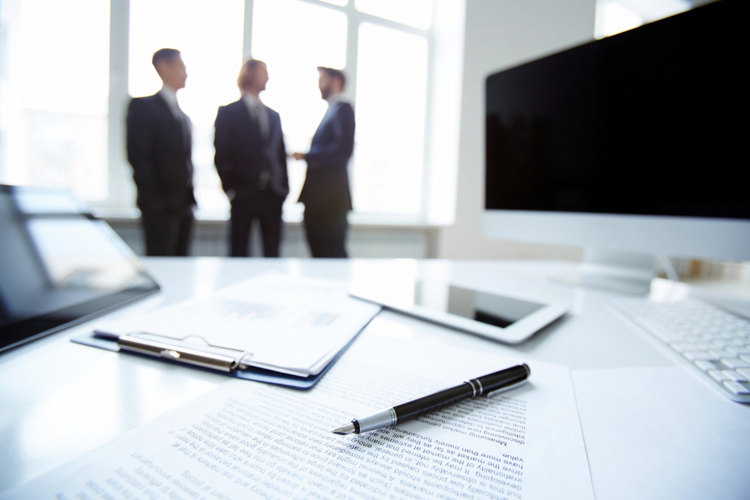 專業責任保險合約文件與鋼筆，背景商務專業人士討論企業保險保障方案。