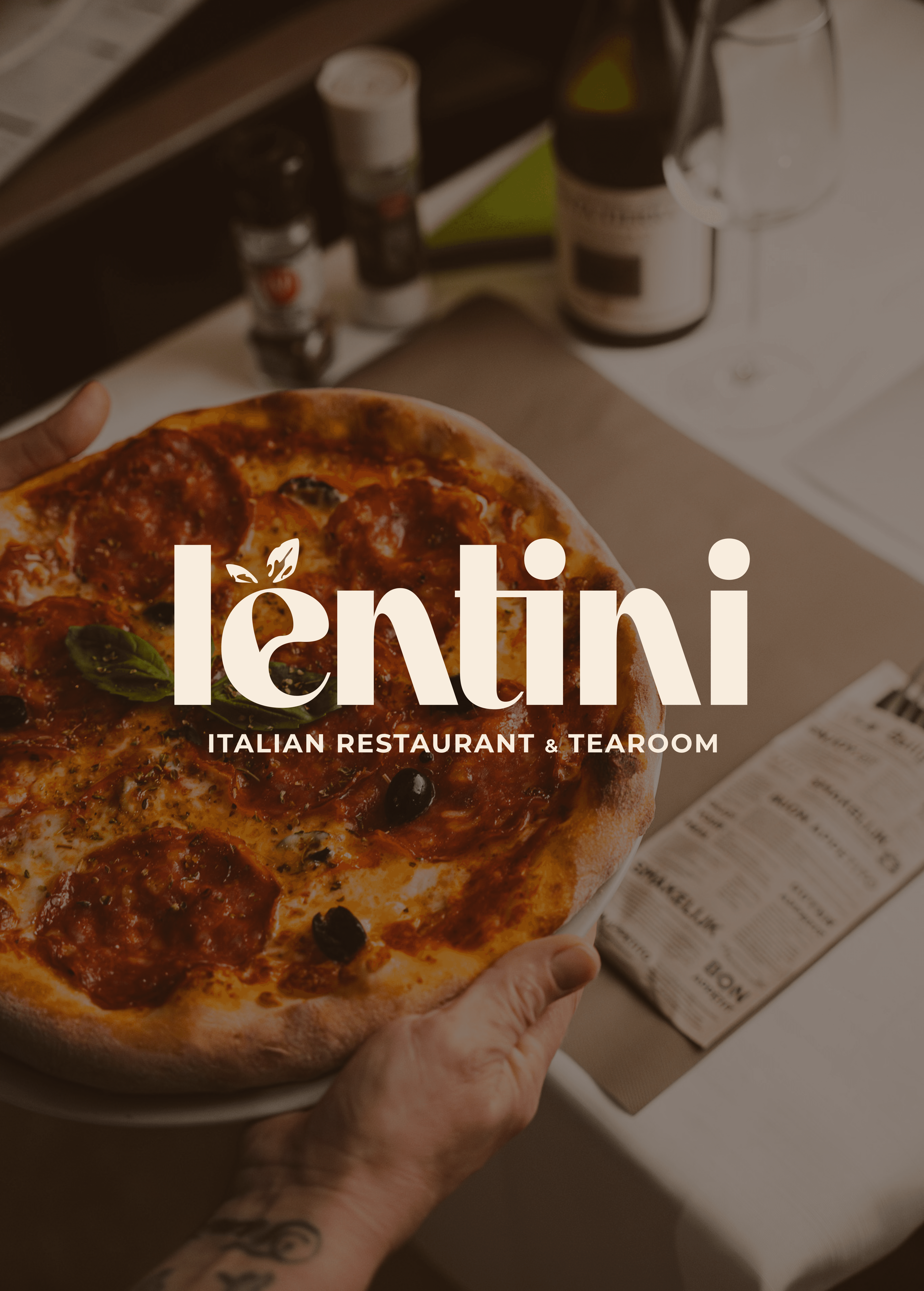 Close-up of a freshly baked pepperoni pizza with basil leaves at Lentini Italian Restaurant & Tearoom, served on a table with wine and menu.