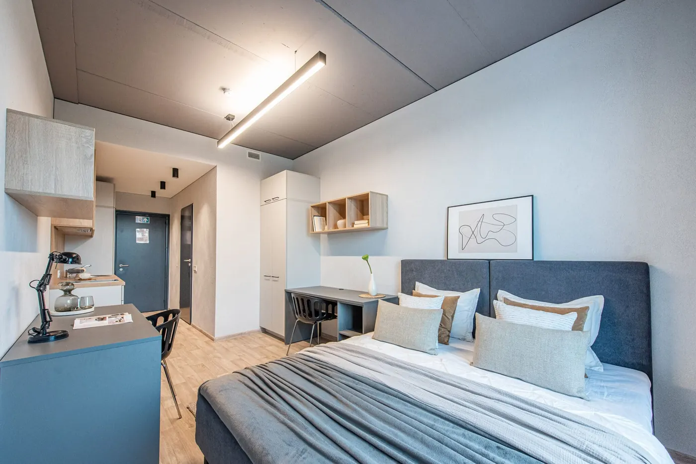 Modern furnished student studio in Vilnius with double bed, private kitchenette, study desk and storage.