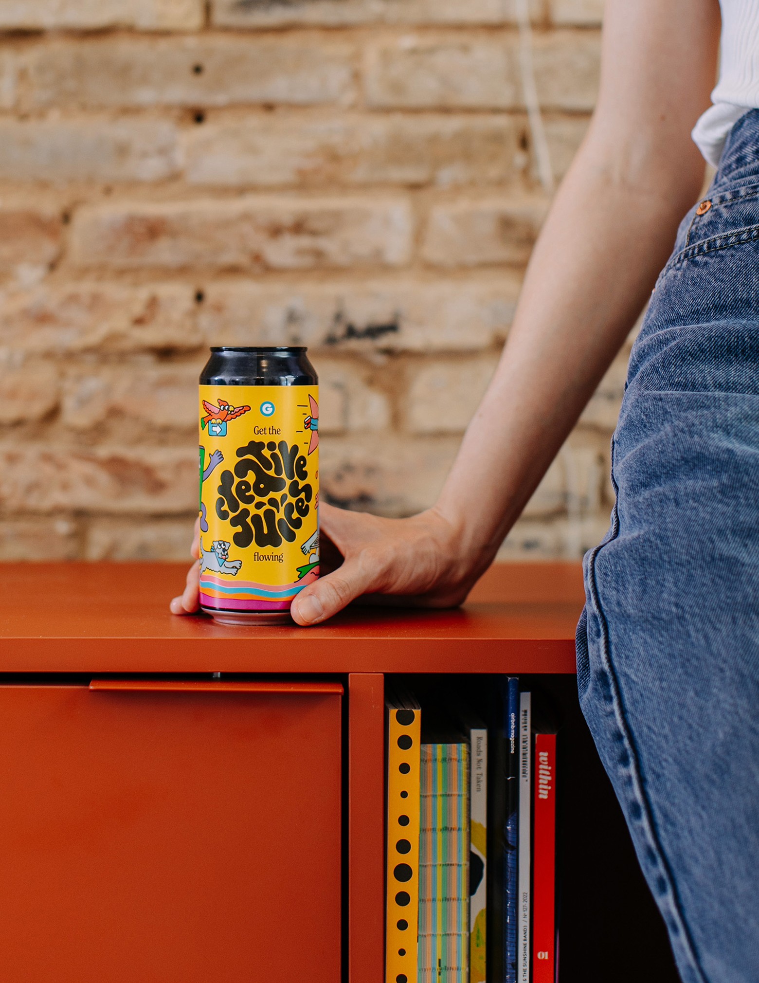 A woman holding a custom beer standing on a furniture