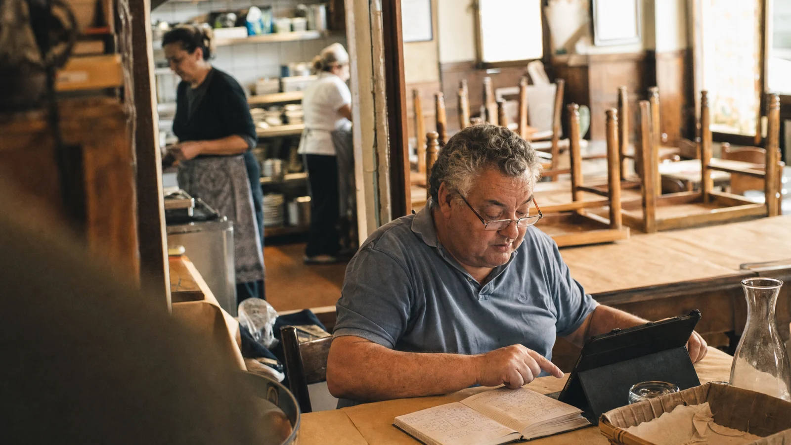 Oste copia i piatti scritti a mano sul quaderno dentro un tablet nella sua trattoria