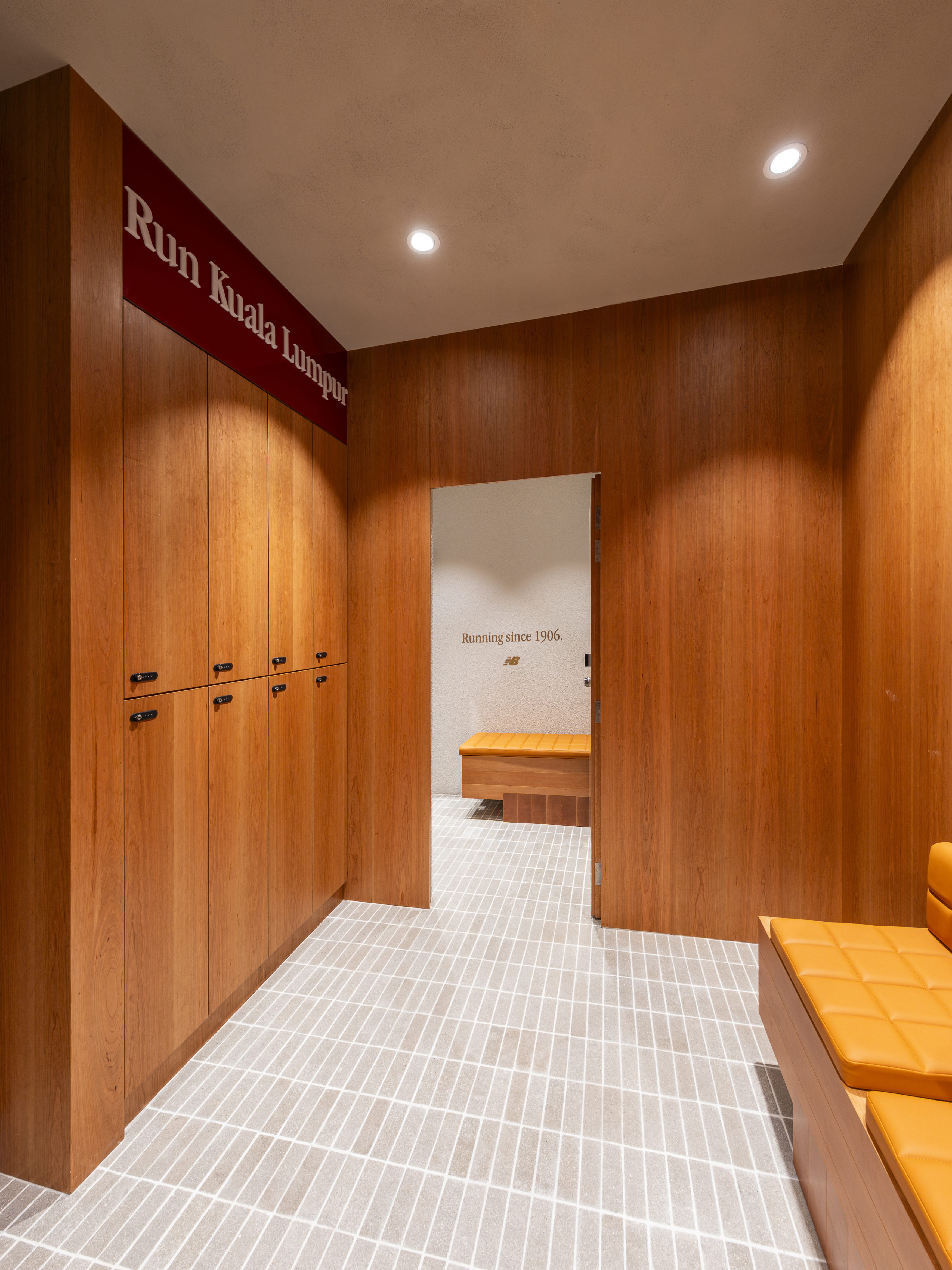 Interior view of the New Balance Run Hub in Suria KLCC, featuring wooden lockers, a bench, and a wall sign that reads 'Run Kuala Lumpur'.