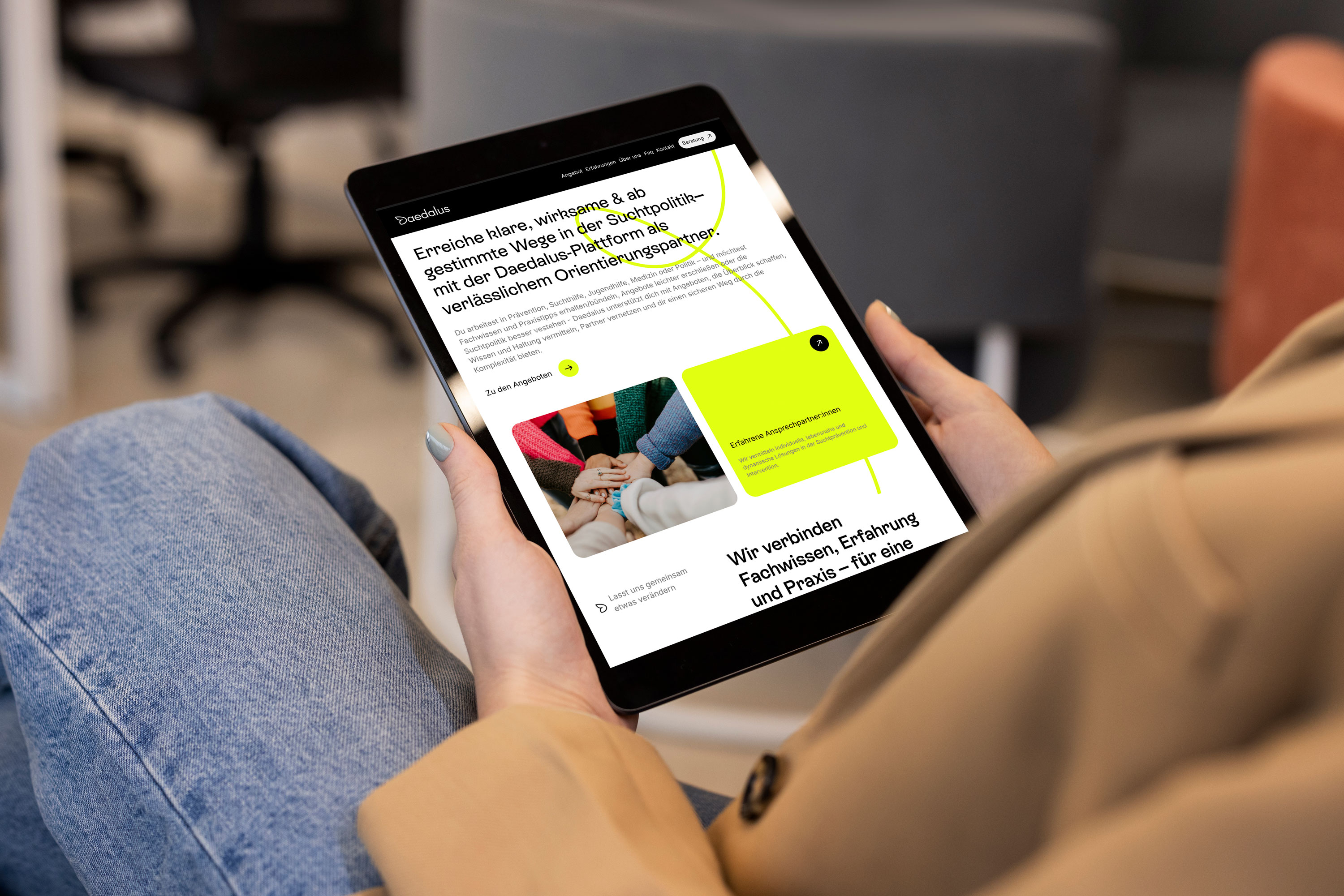 I pad mit webdesign in den Händen einer Frau mit beigem Mantel