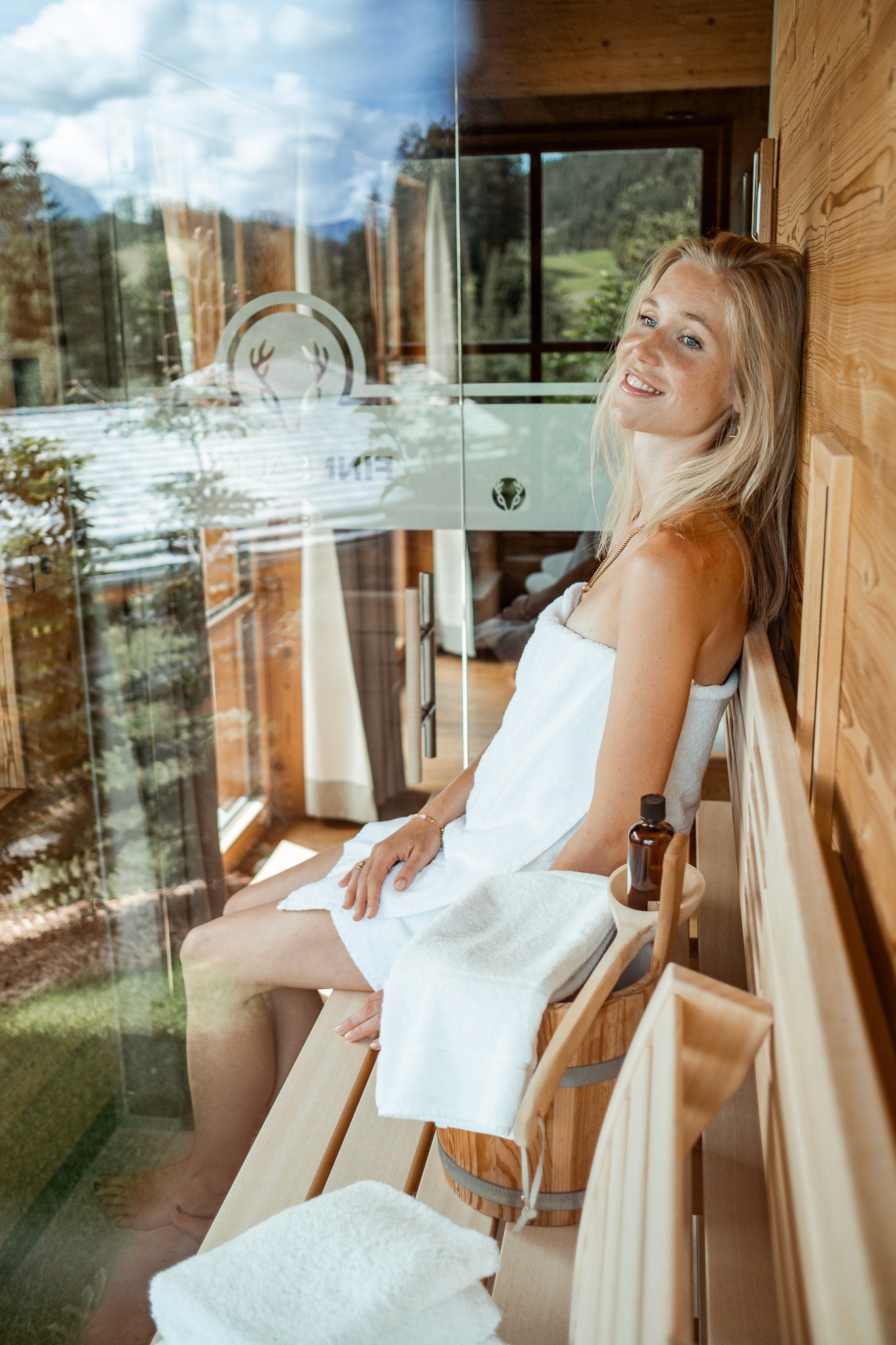 Frau in privater Sauna im Chalet mit Panoramablick auf die österreichischen Alpen – pure Entspannung