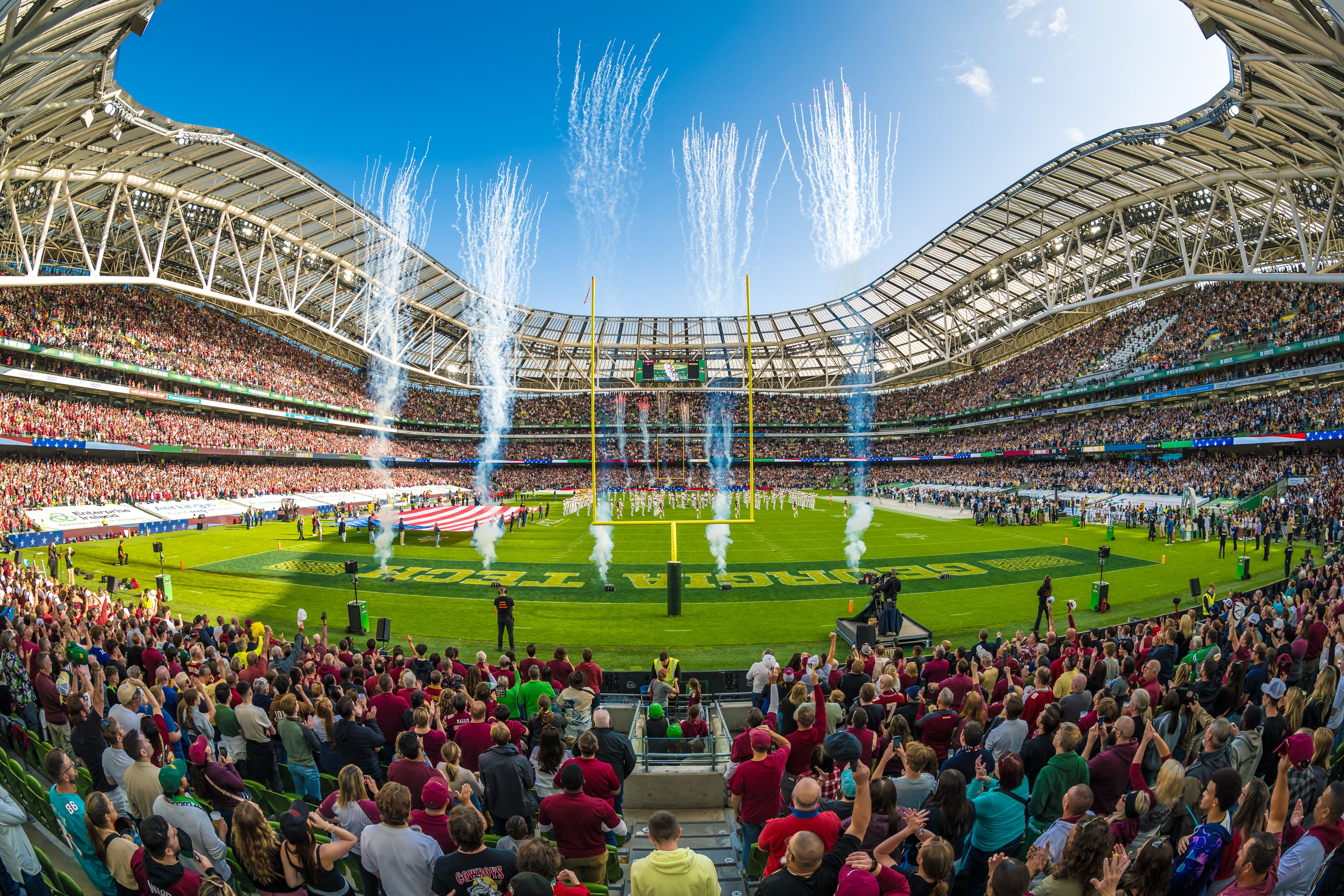 A vibrant, wide-angle view of a packed Aviva Stadium in Dublin, Ireland, filled with enthusiastic fans as fireworks erupt over the field during the Aer Lingus College Football Classic. Investicon is a proud partner, celebrating the spirit of "More Than Just a Game." #AerLingusCollegeClassic #AvivaStadium #DublinEvents #CollegeFootballIreland #GameDay #InvesticonPartner