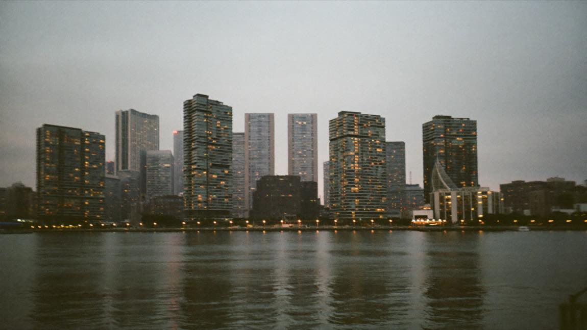 Long Island City waterfront residential towers at dusk seen across the East River