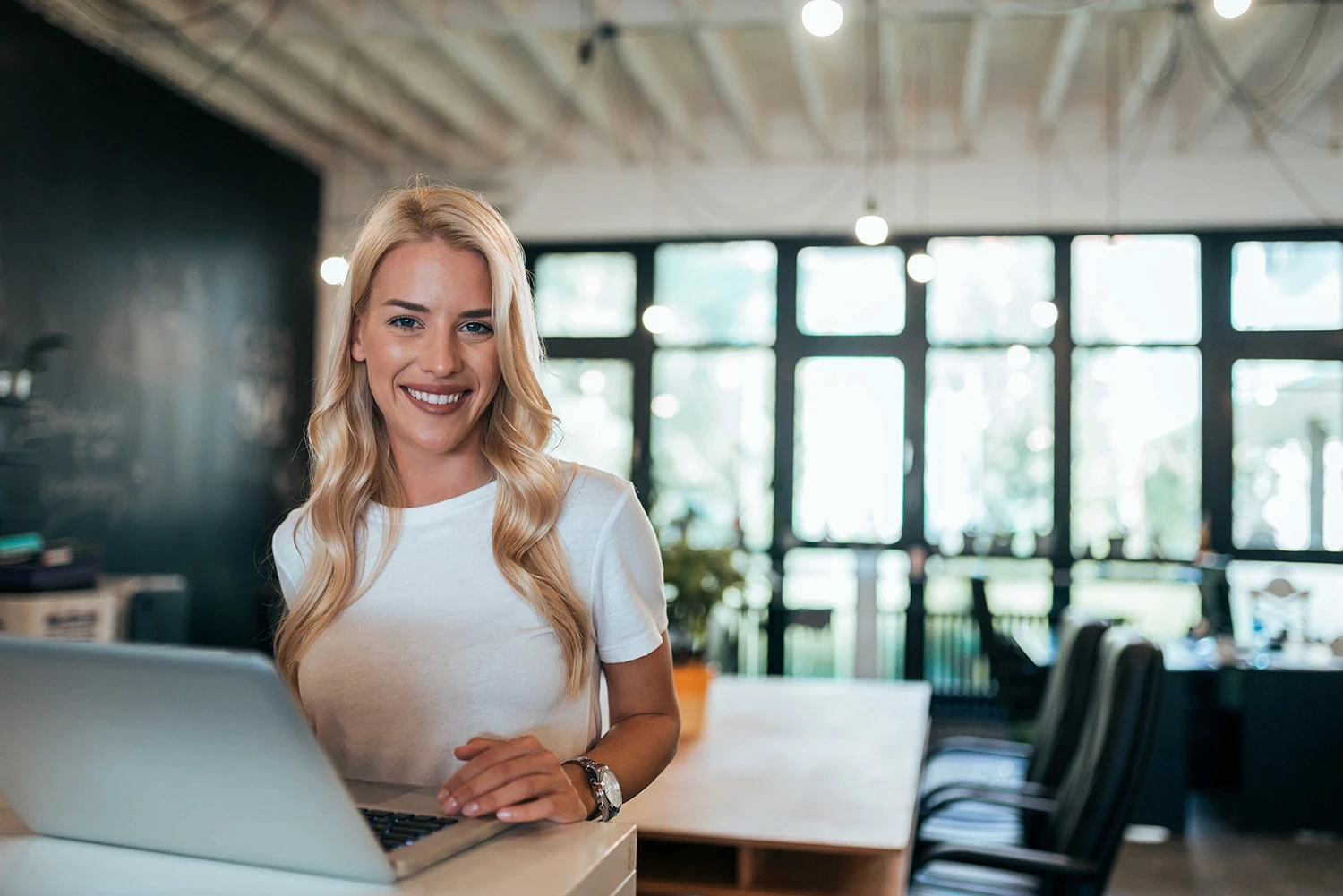 Digital video expert sitting at a laptop and smiling while editing content.
