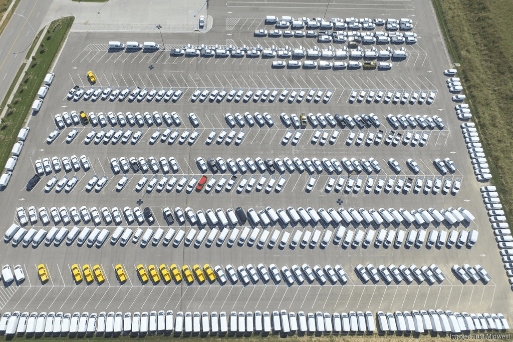 Overhead view of a vehicle storage lot filled with vans and trucks