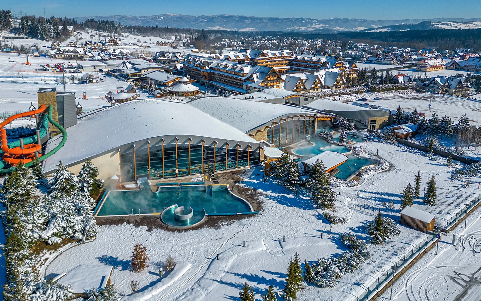 Aerial view of Zakopane Thermal Bath with snow-covered landscape and outdoor pools.