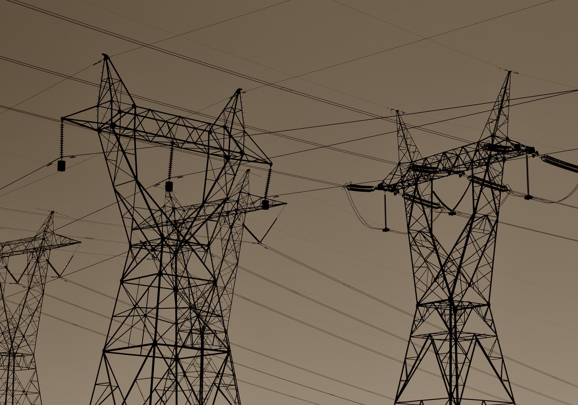 High-voltage electrical transmission towers and power lines against a dusk sky, representing grid infrastructure.